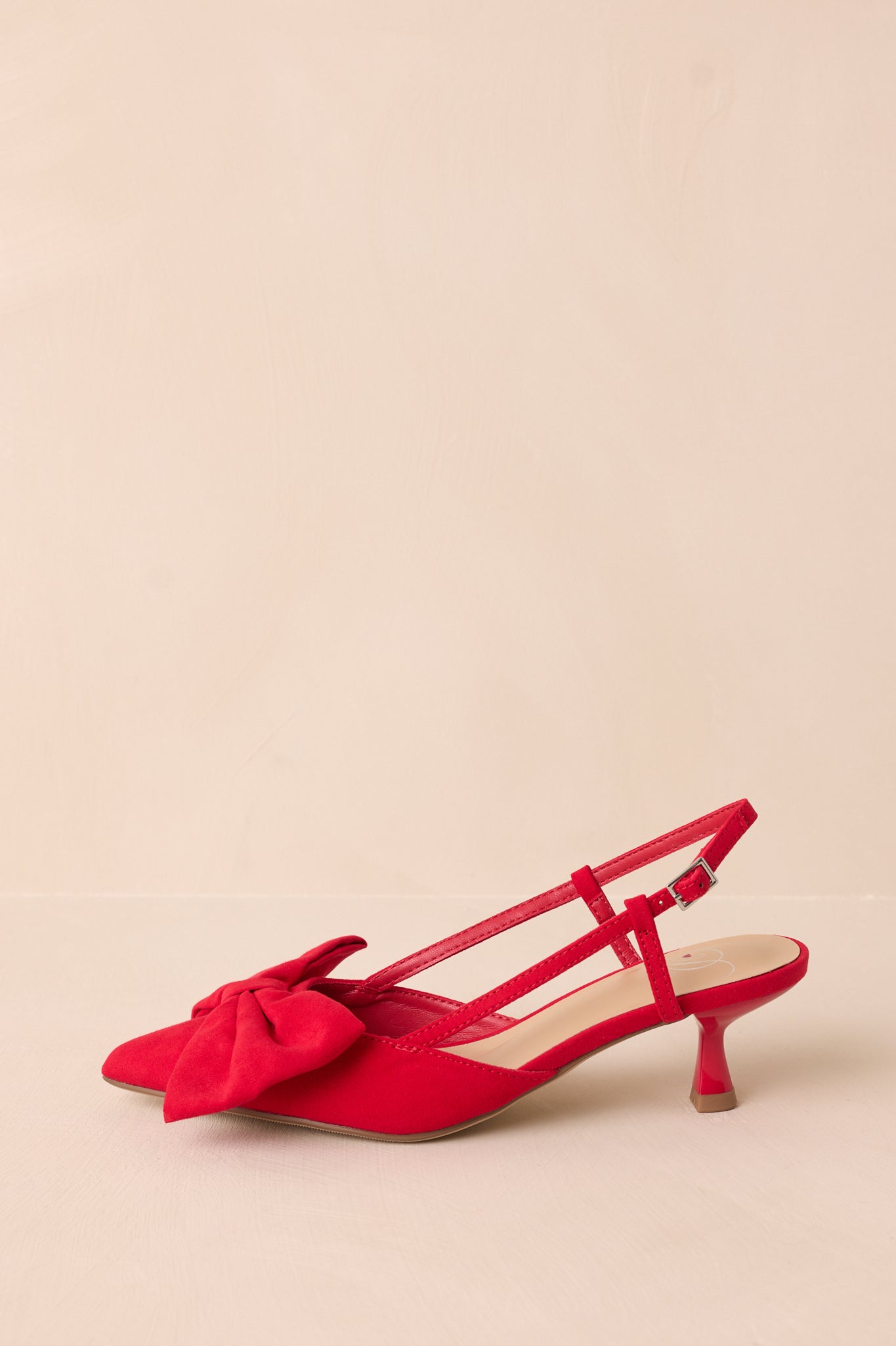 Side view of the red kitten heels, highlighting the ankle strap with its gold buckle and the small, refined kitten heel.