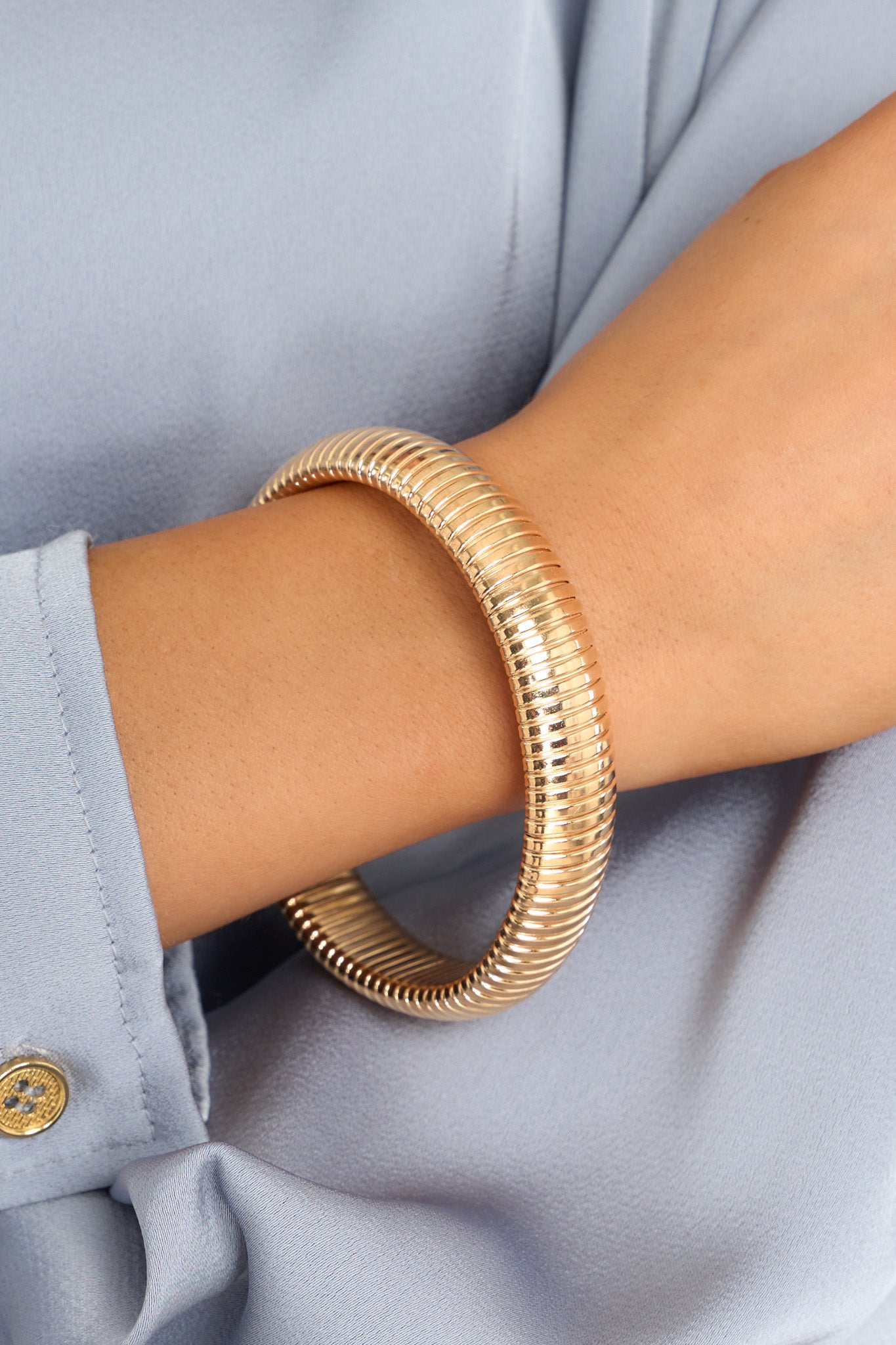 This gold bracelet features a circular, slip-on design with ridge detailing.