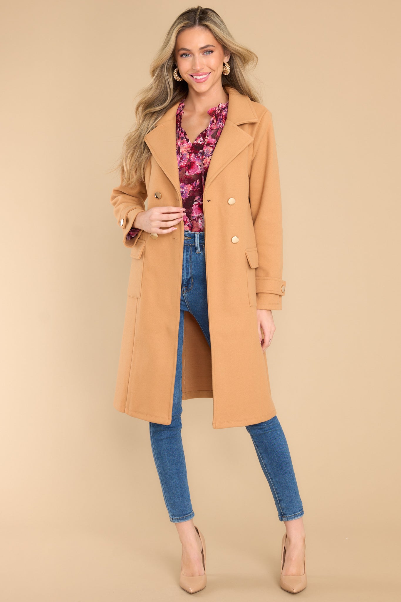 This camel colored coat features a collared neckline and functional buttons and pockets. 