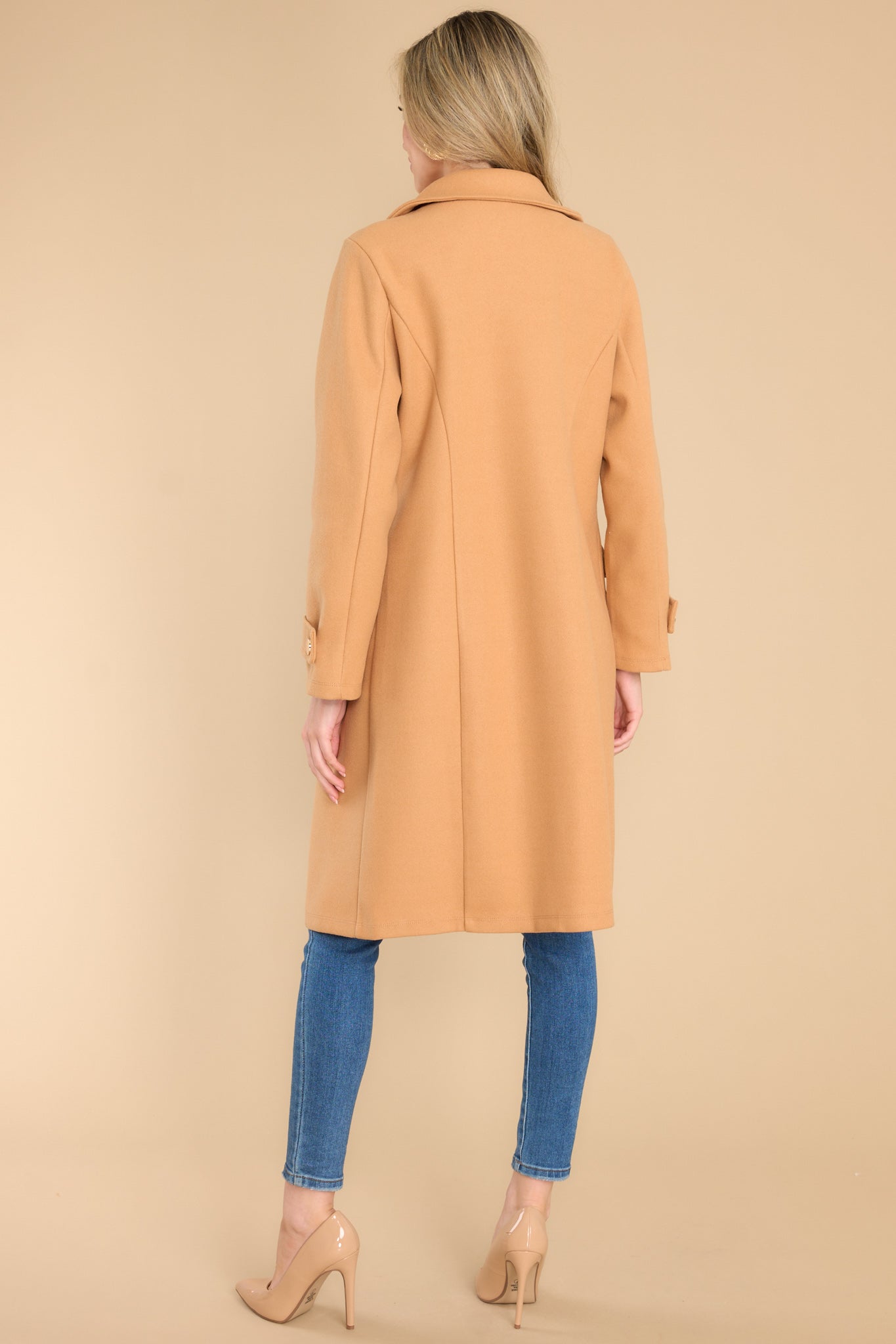 Back view of this coat that features a collared neckline and functional buttons and pockets.