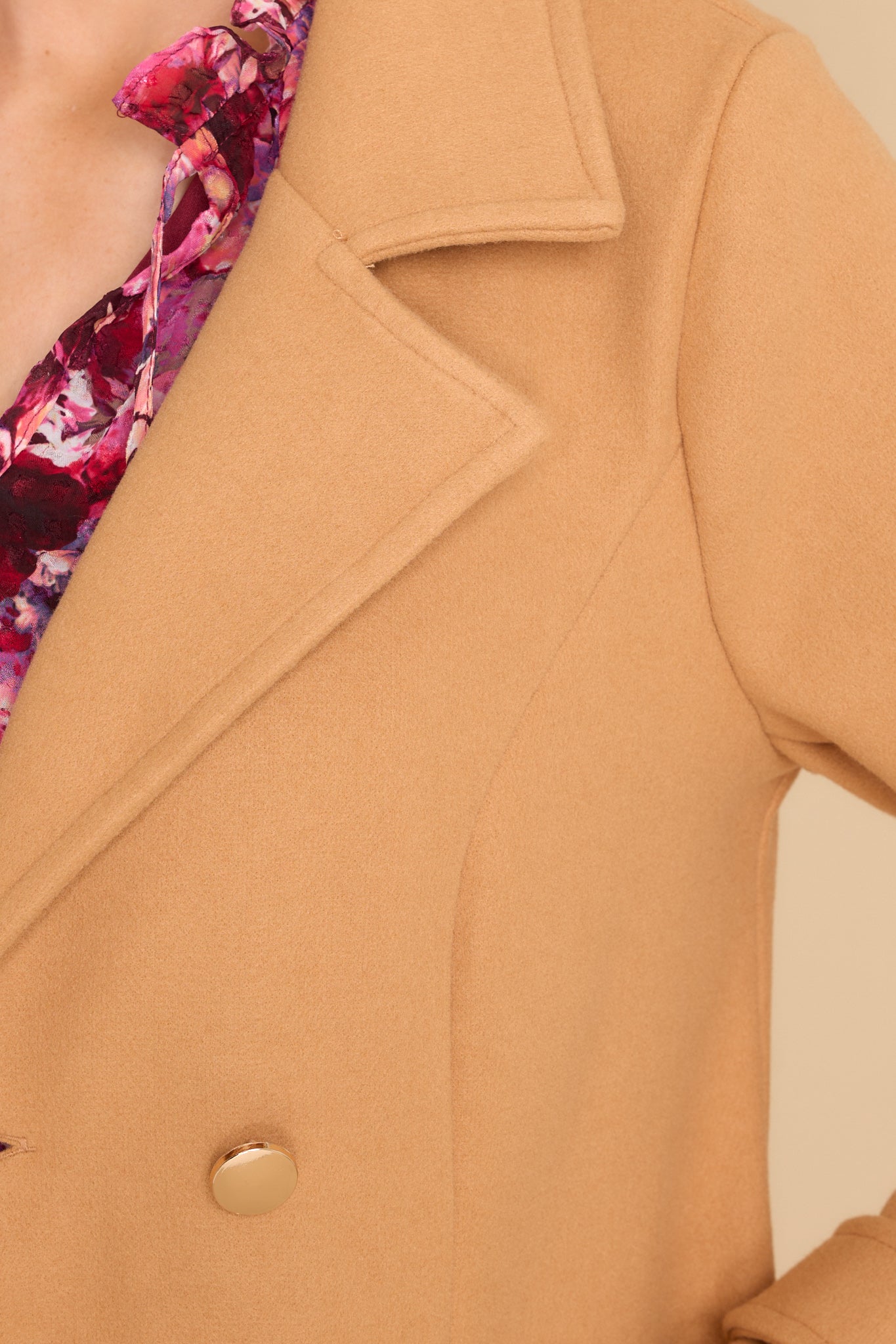 Close up view of this coat that features a collared neckline and functional buttons and pockets. 