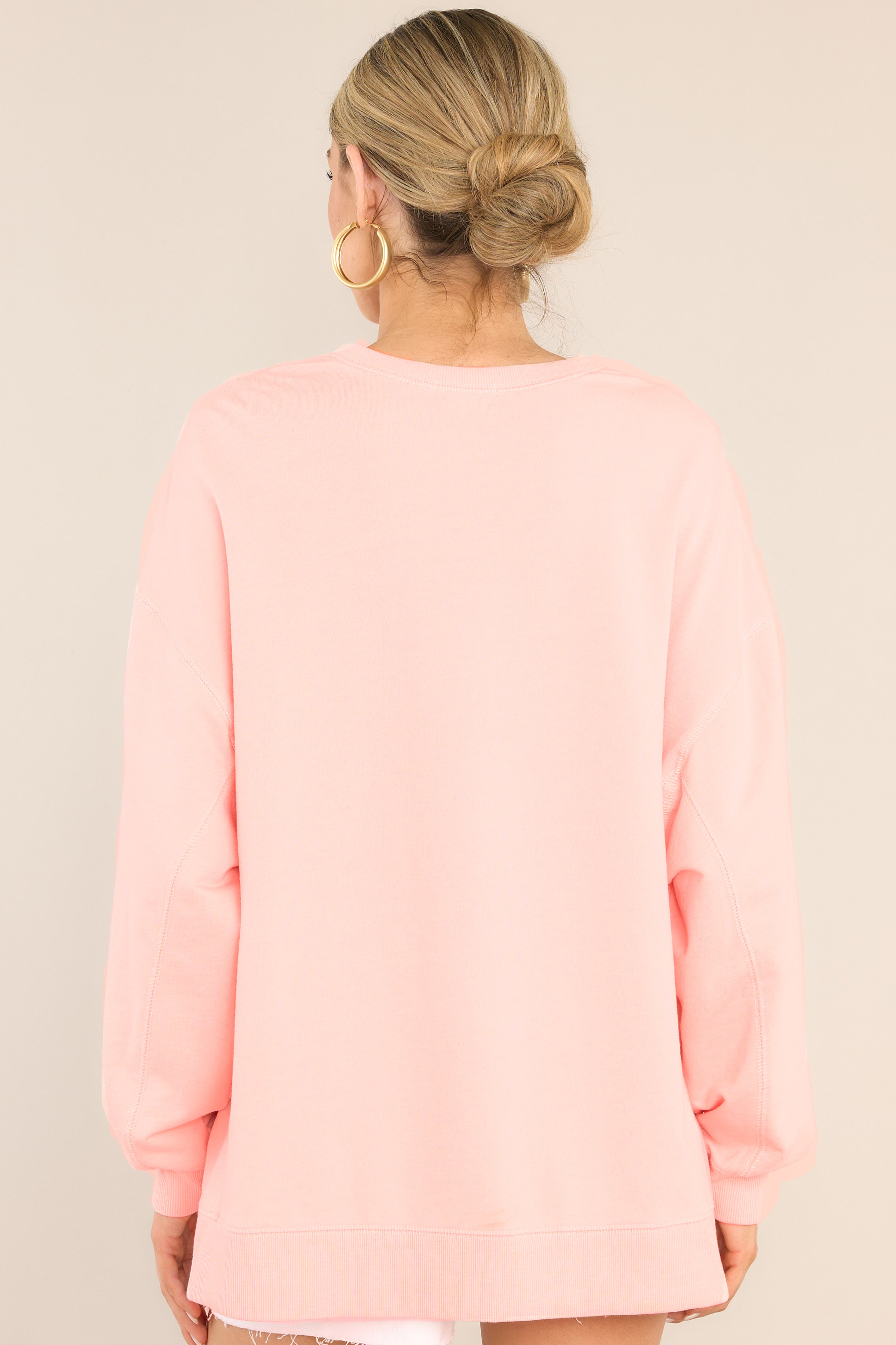 Back view of this top that features a ribbed crew neckline, dropped shoulders, exposed seams, ribbed cuffed sleeves, and a ribbed split high-low hemline.