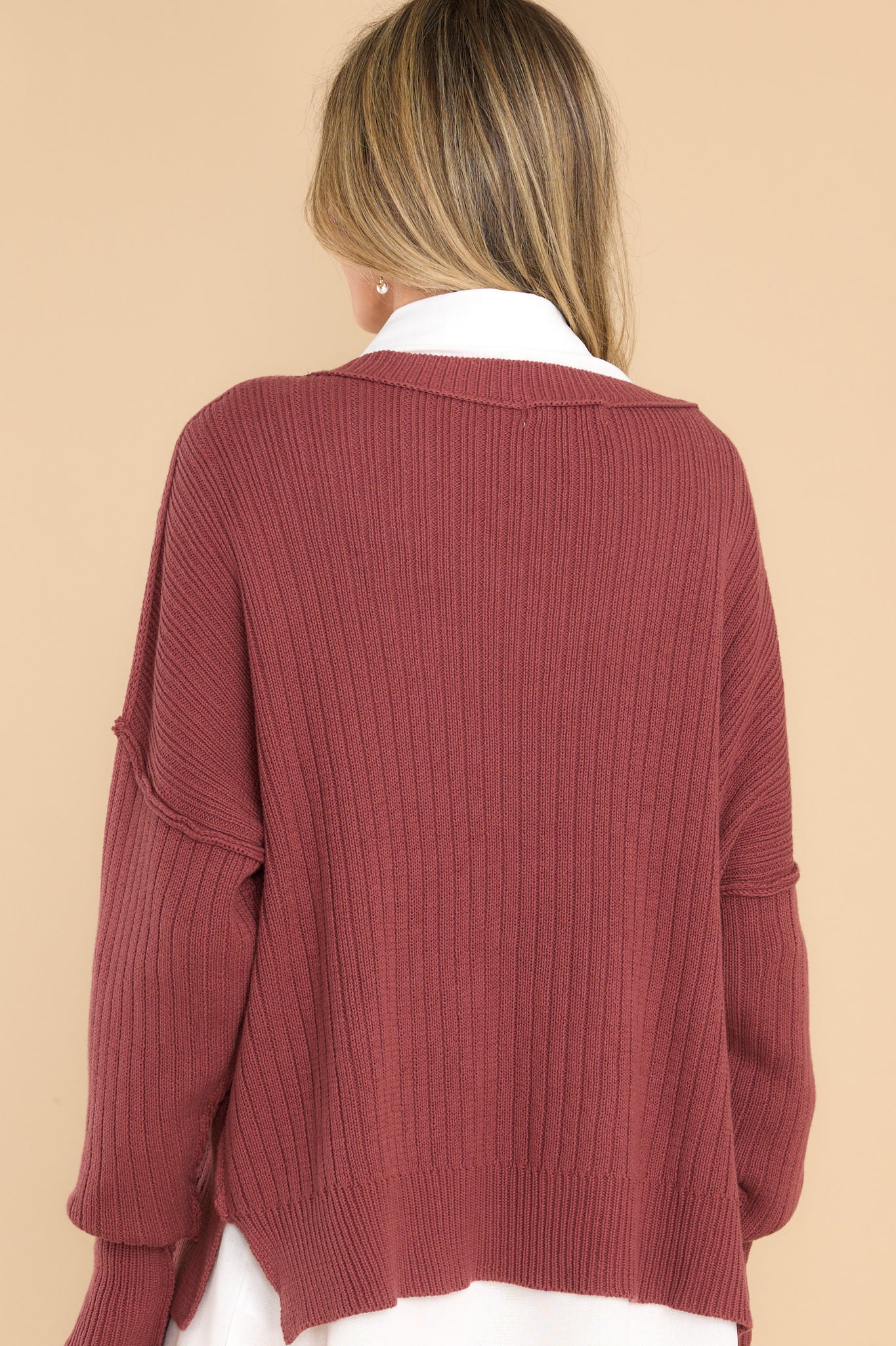 Back view of this sweater that features a v-neckline, long sleeves with tapered cuffs, small slits up the bottom hem on both sides, and a knit texture throughout.