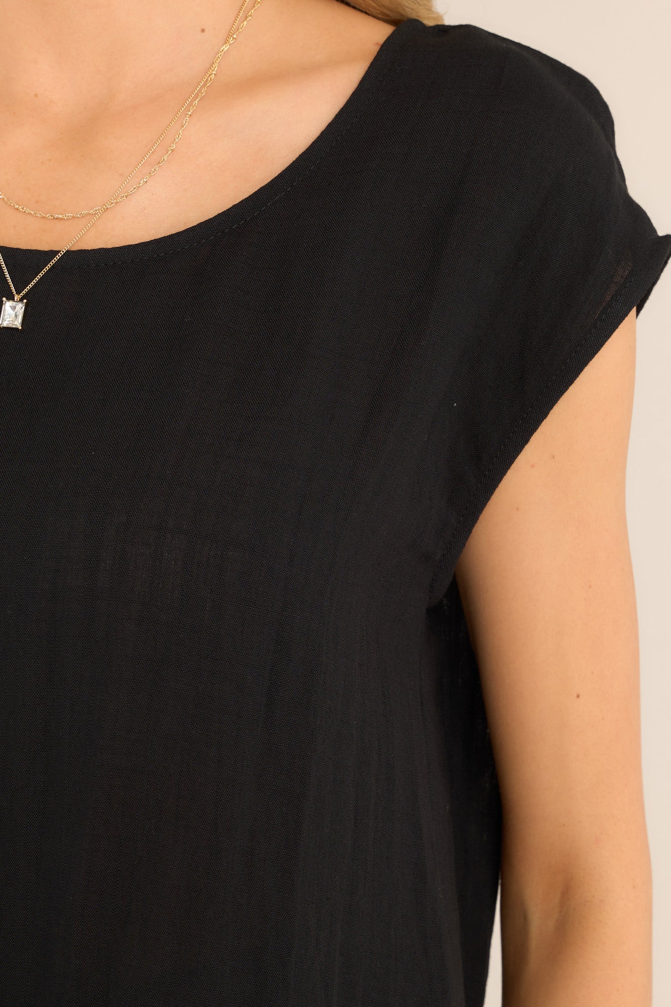 Close up view of this top that features a cap sleeve design, a crew neckline, slightly cropped length, and breezy lightweight fabric. 