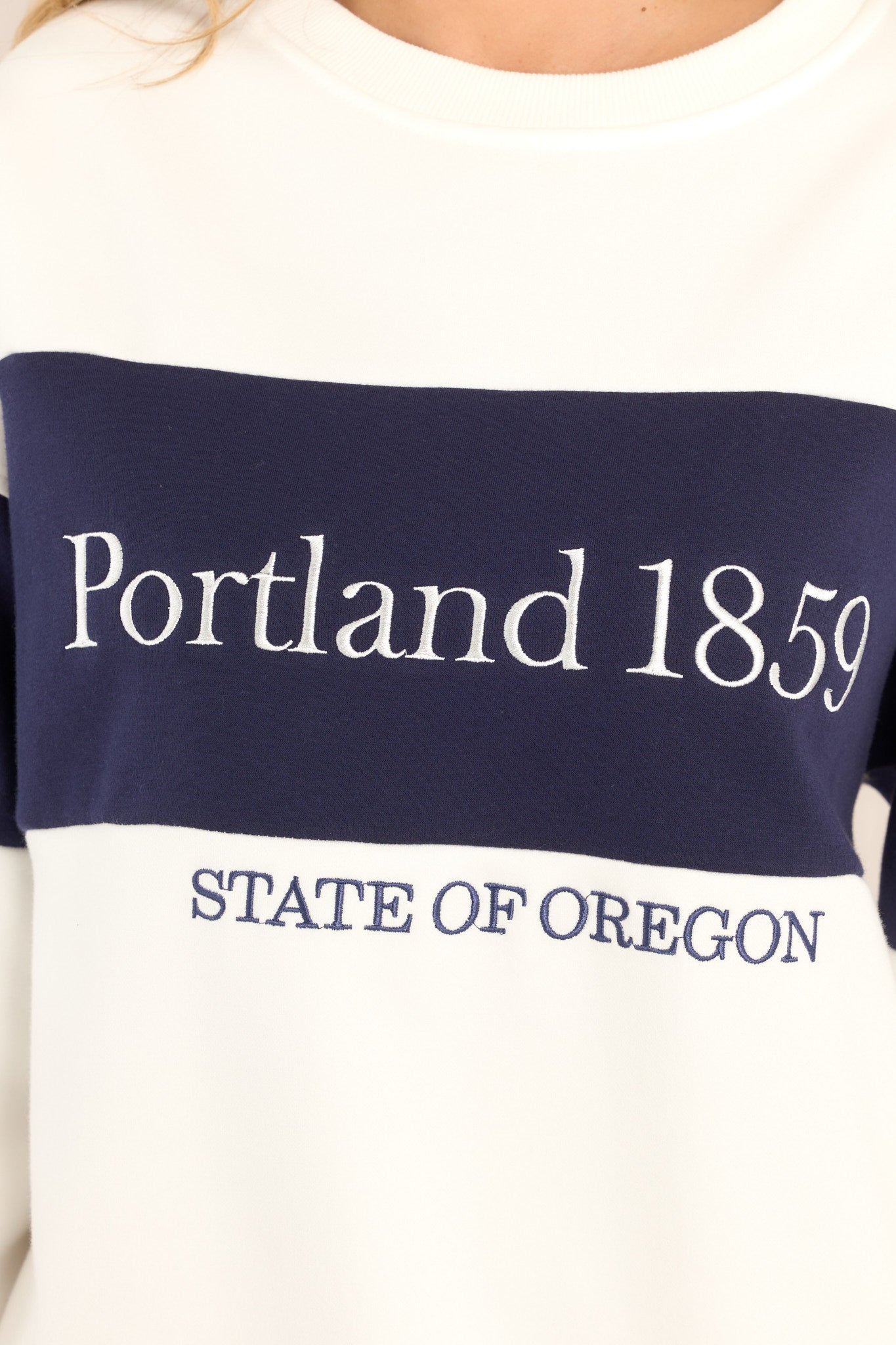 Close up view of this sweatshirt that features embroidered "Portland 1859" and "STATE OF OREGON" text and a crew neckline.