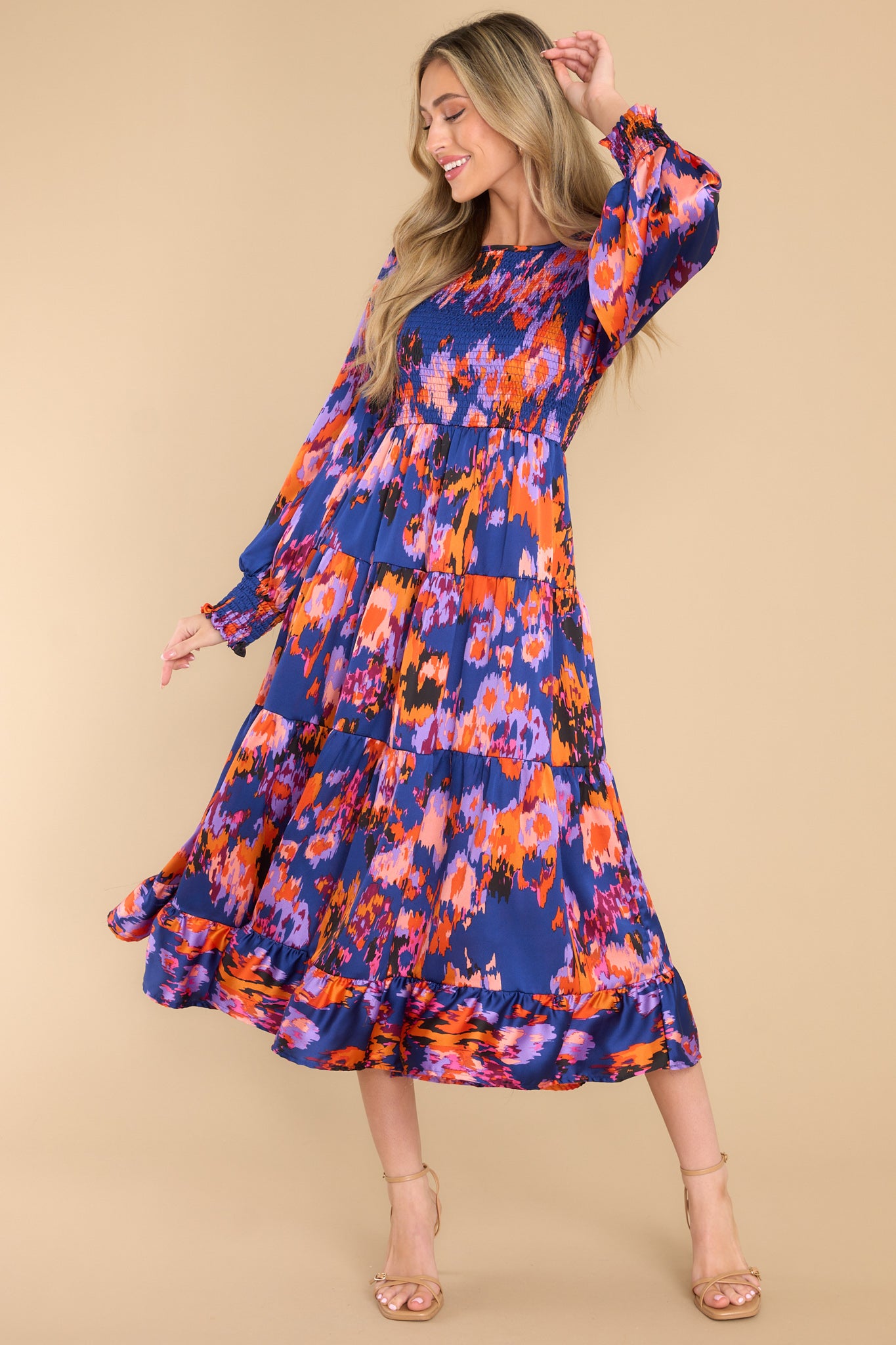 Full body view of this dress that features a crew neckline, a keyhole closure in the back, a fully smocked bodice, a tiered design, smocked sleeves, and an abstract print. 