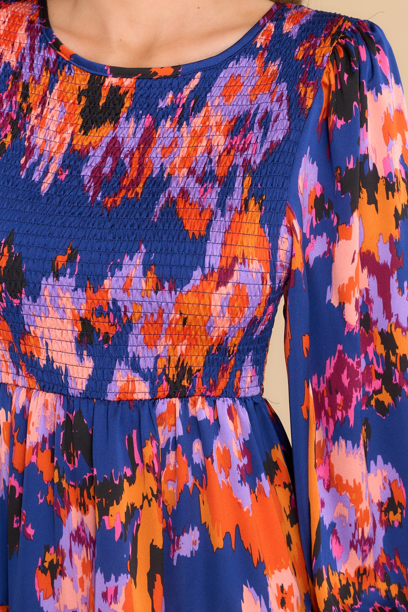 Close up view of this dress that features a crew neckline, a fully smocked bodice, and an abstract print. 