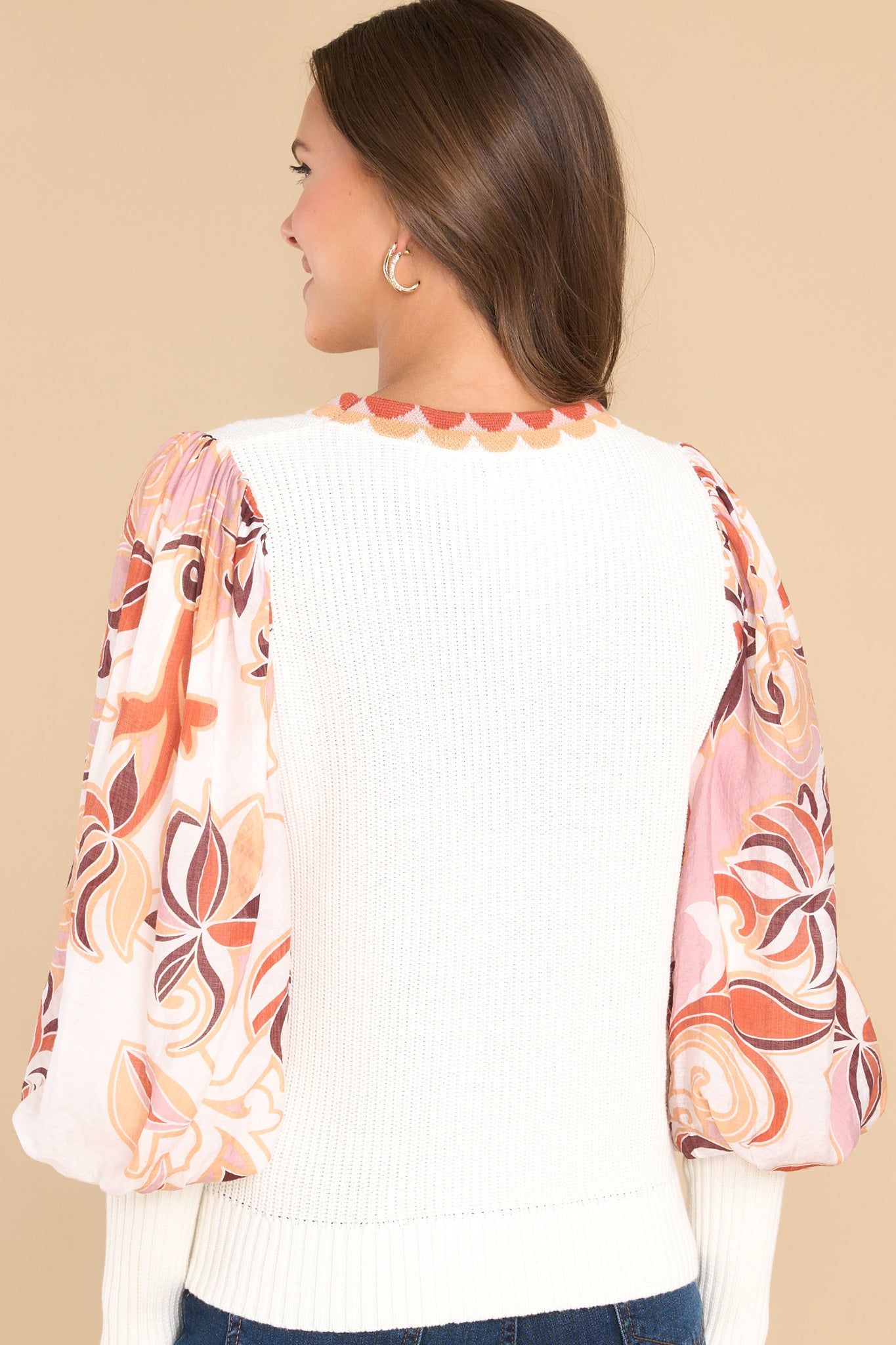 Back view of this top that features a round neckline, sheer bishop sleeves with long ribbed cuffs, and mixed white and printed design.