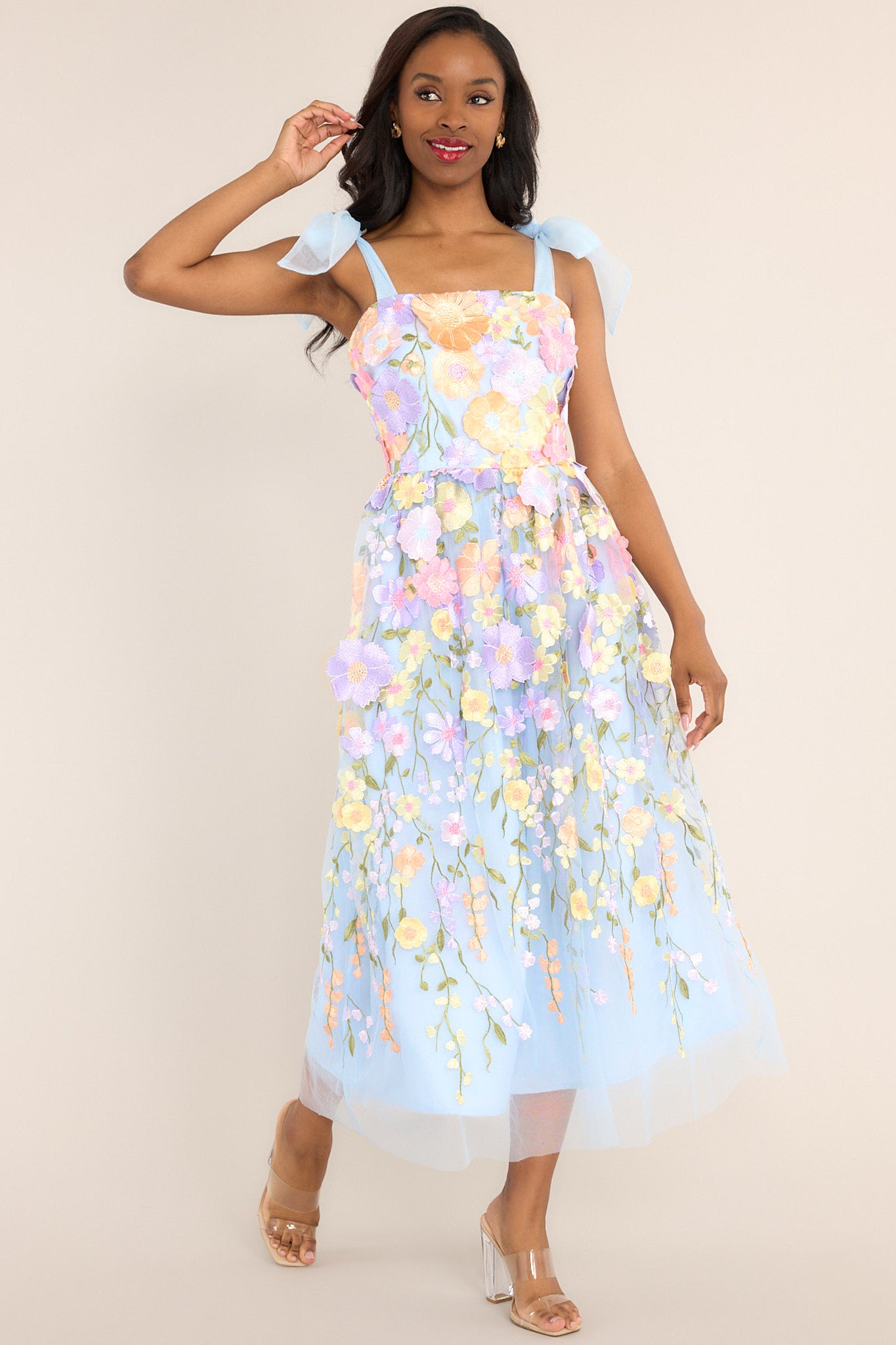 Full body view of this dress features a square neckline, tulle ribbon self-tie straps, a hidden zipper at the back, and an embroidered floral design throughout the dress.