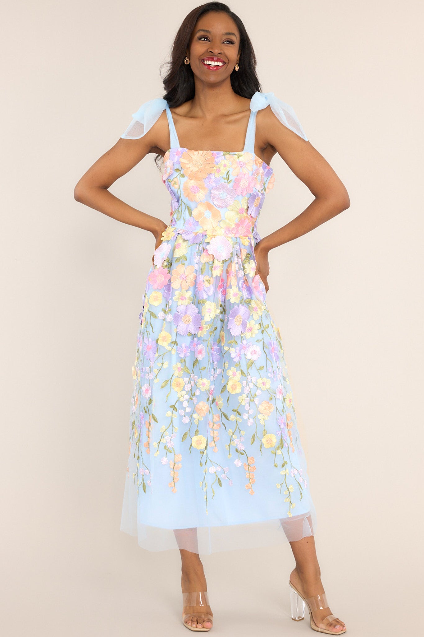 Full front view of this dress features a square neckline, tulle ribbon self-tie straps, a hidden zipper at the back, and an embroidered floral design throughout the dress.