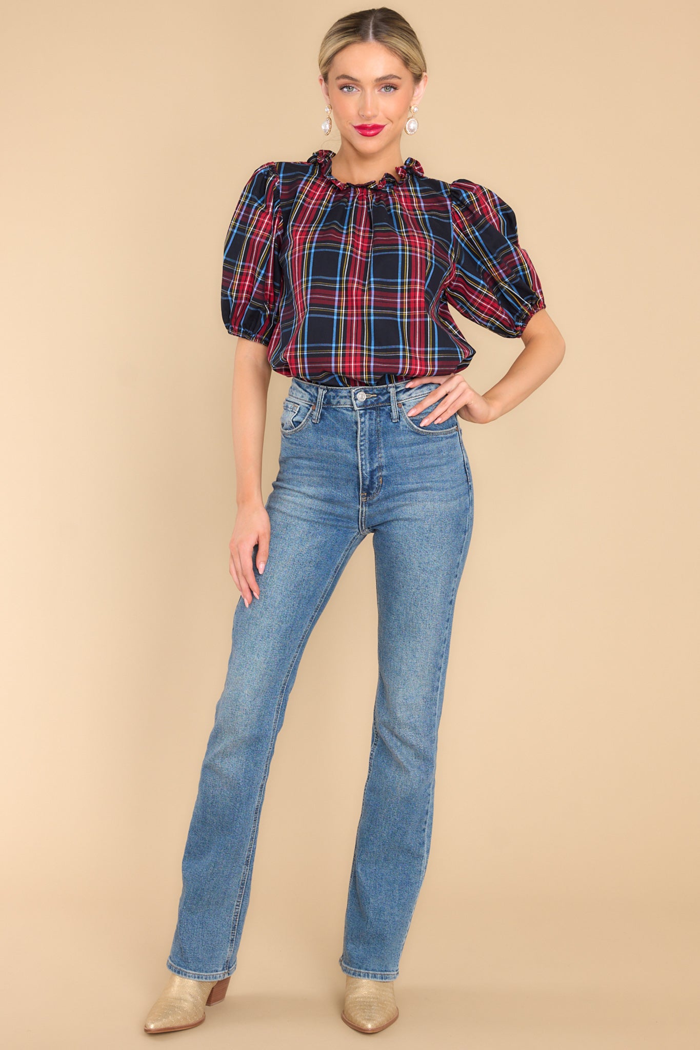 Full body view of this top that features a ruffled neckline, a keyhole closure in the back, elastic cuffed puffy sleeves, and a plaid pattern.