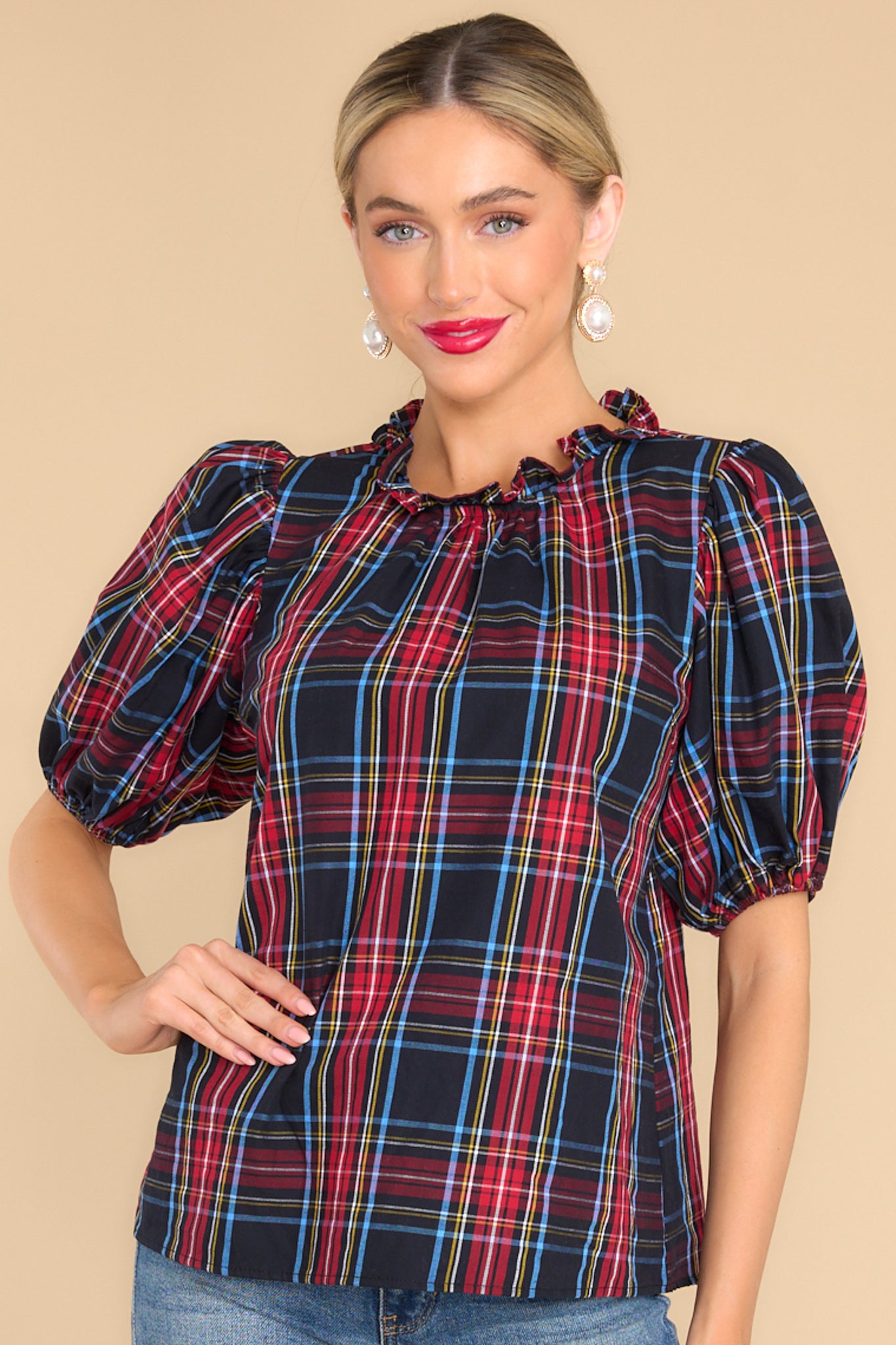 Front view of this top untucked that features a ruffled neckline, elastic cuffed puffy sleeves, and a plaid pattern.