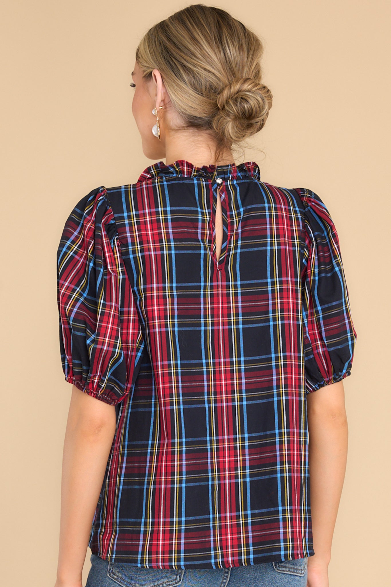 Back view of this top that features a ruffled neckline, a keyhole closure in the back, elastic cuffed puffy sleeves, and a plaid pattern.
