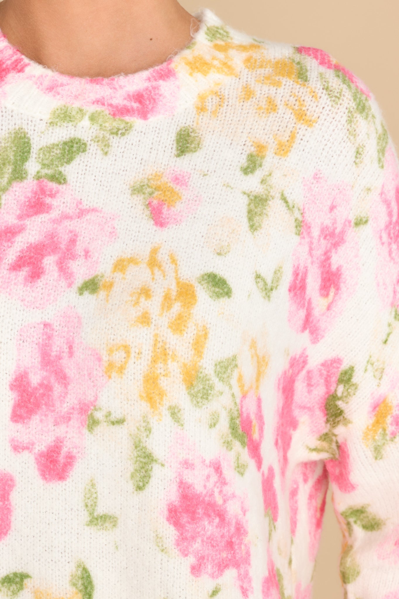 Close up view of this sweater that features a crew neckline, an all over floral print, and cuffed sleeves. 