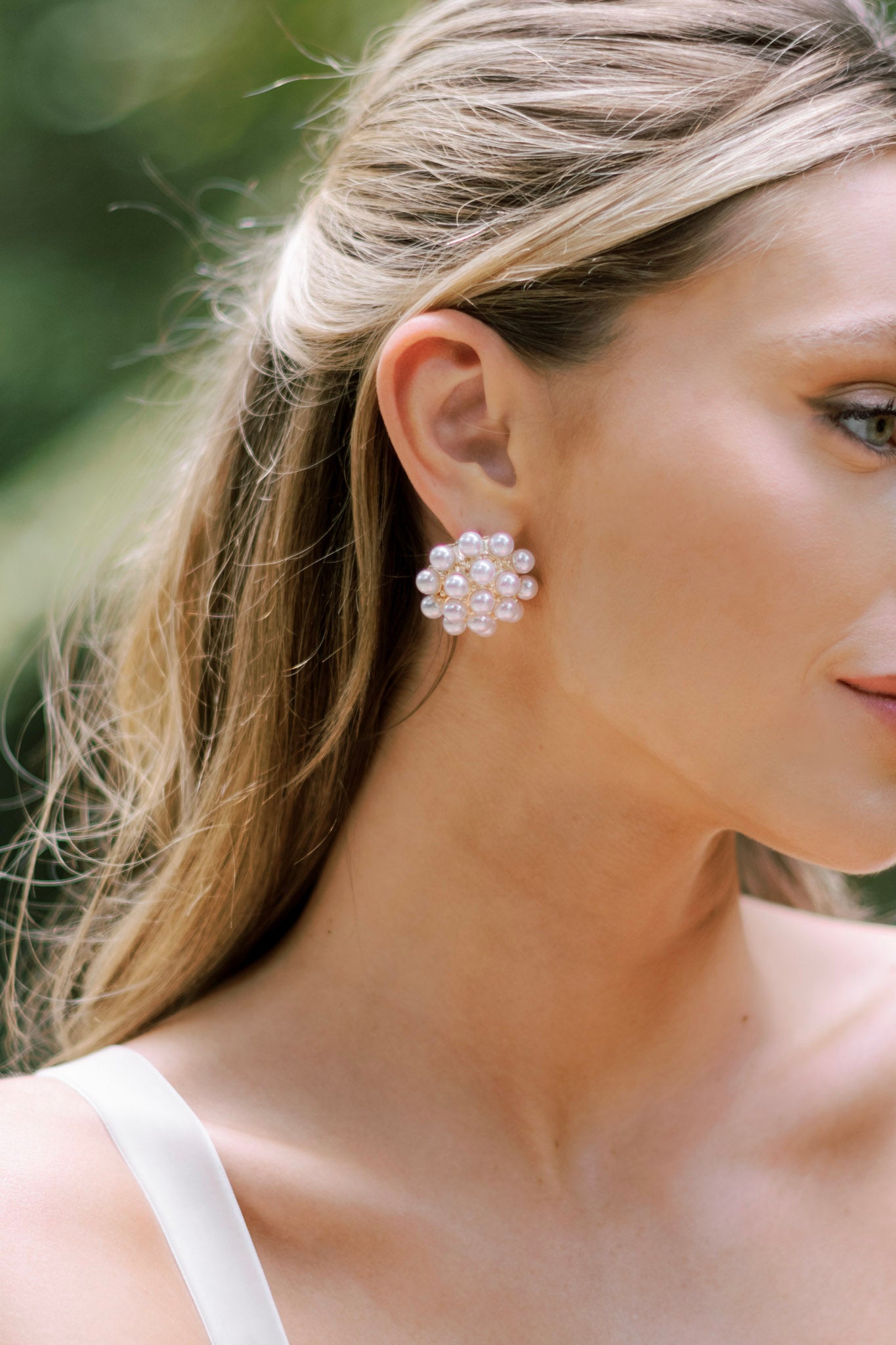 These earrings feature gold hardware, faux ivory pearl clusters, a dome-like shape, and secure post backings.