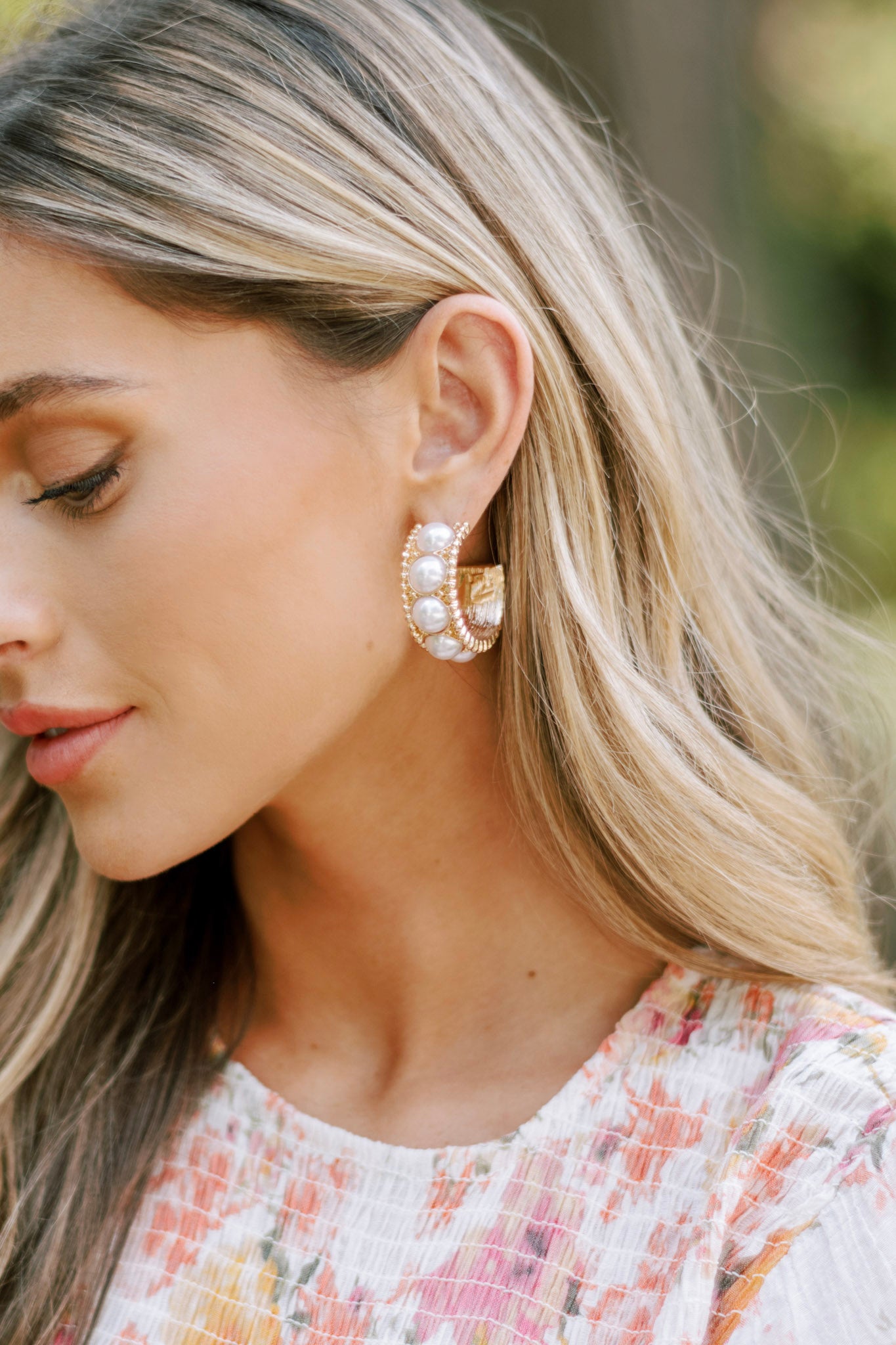 These gold pearl earrings feature gold hardware, a chunky hoop design with evenly spaced pearl embellishments, and a secure post backings.