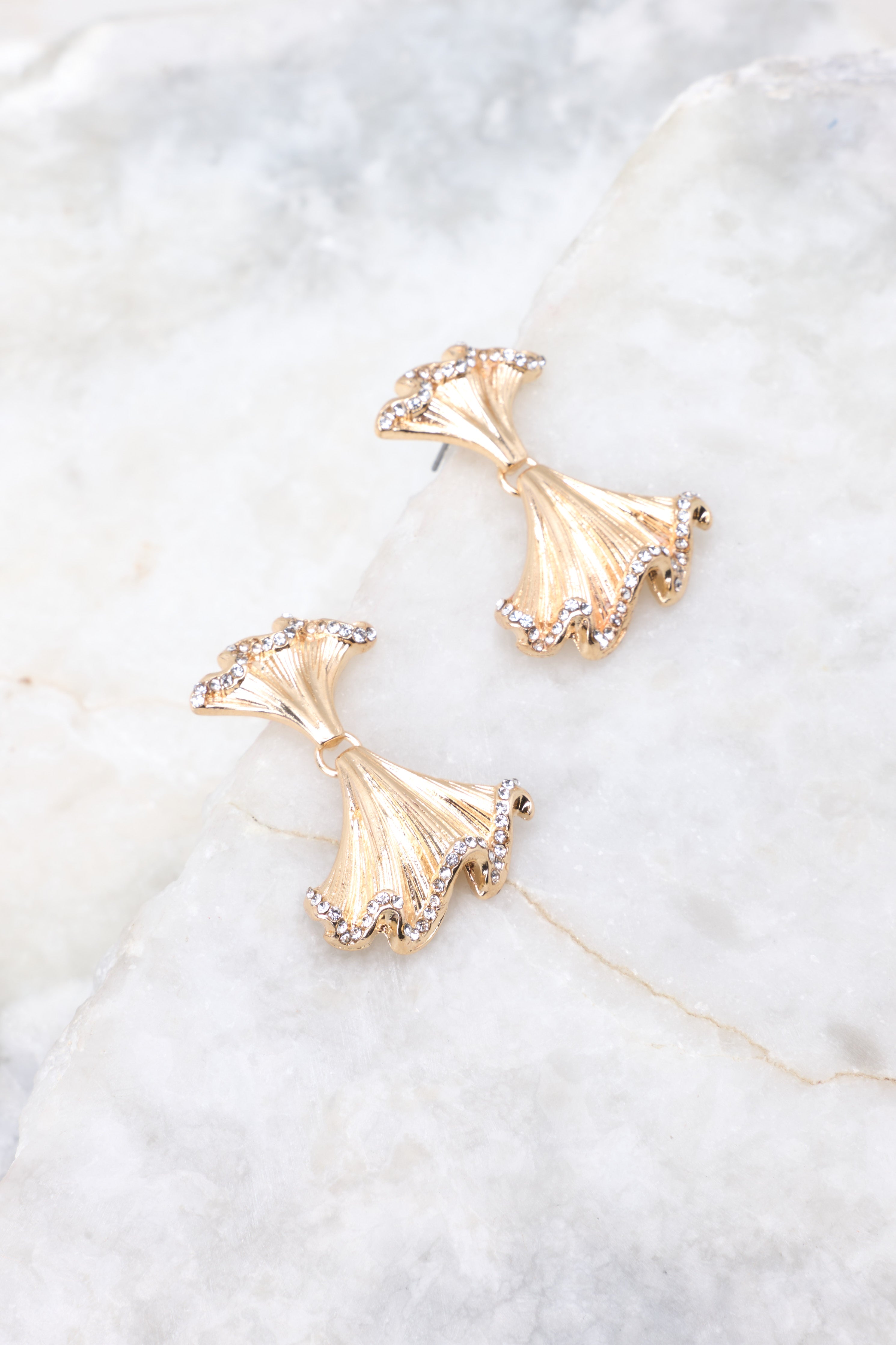 Detailed view of earrings that feature gold hardware, small rhinestone detailing, and a secure post backing.