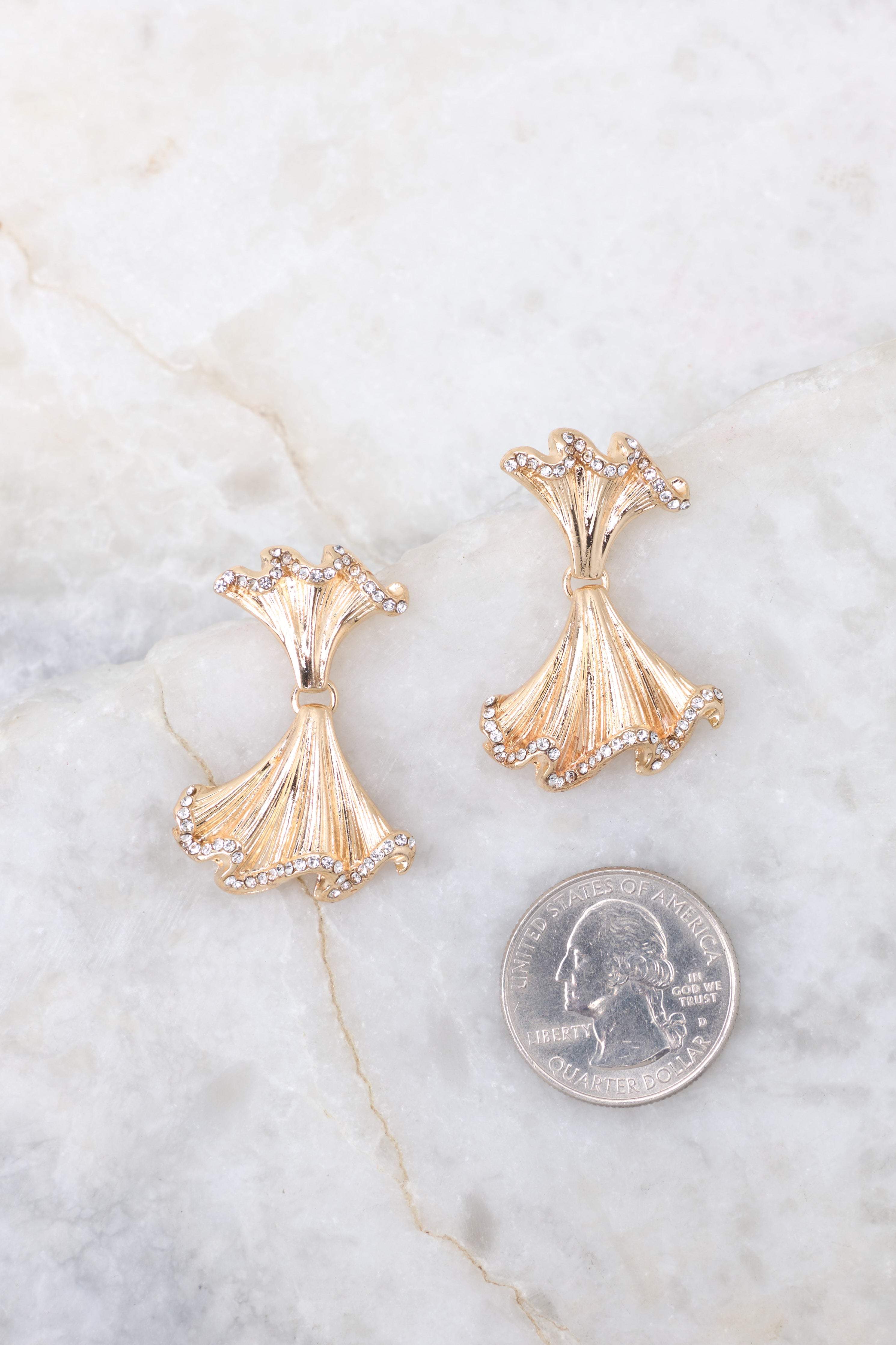 Rhinestone encrusted gold earrings compared to quarter for actual size. Earrings measure 1.5".