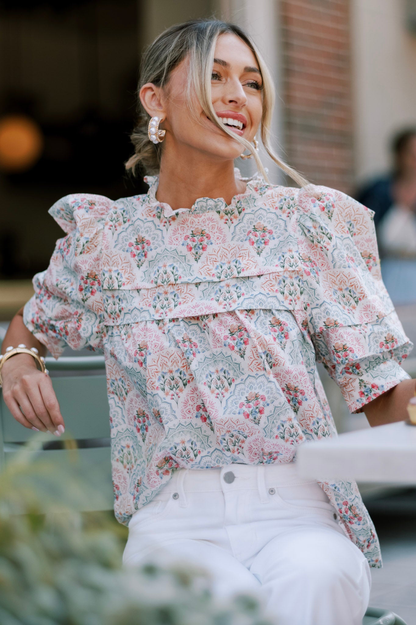 Pastel floral print top with a high neckline and ruffled details, featuring puffed sleeves and an intricate floral pattern.