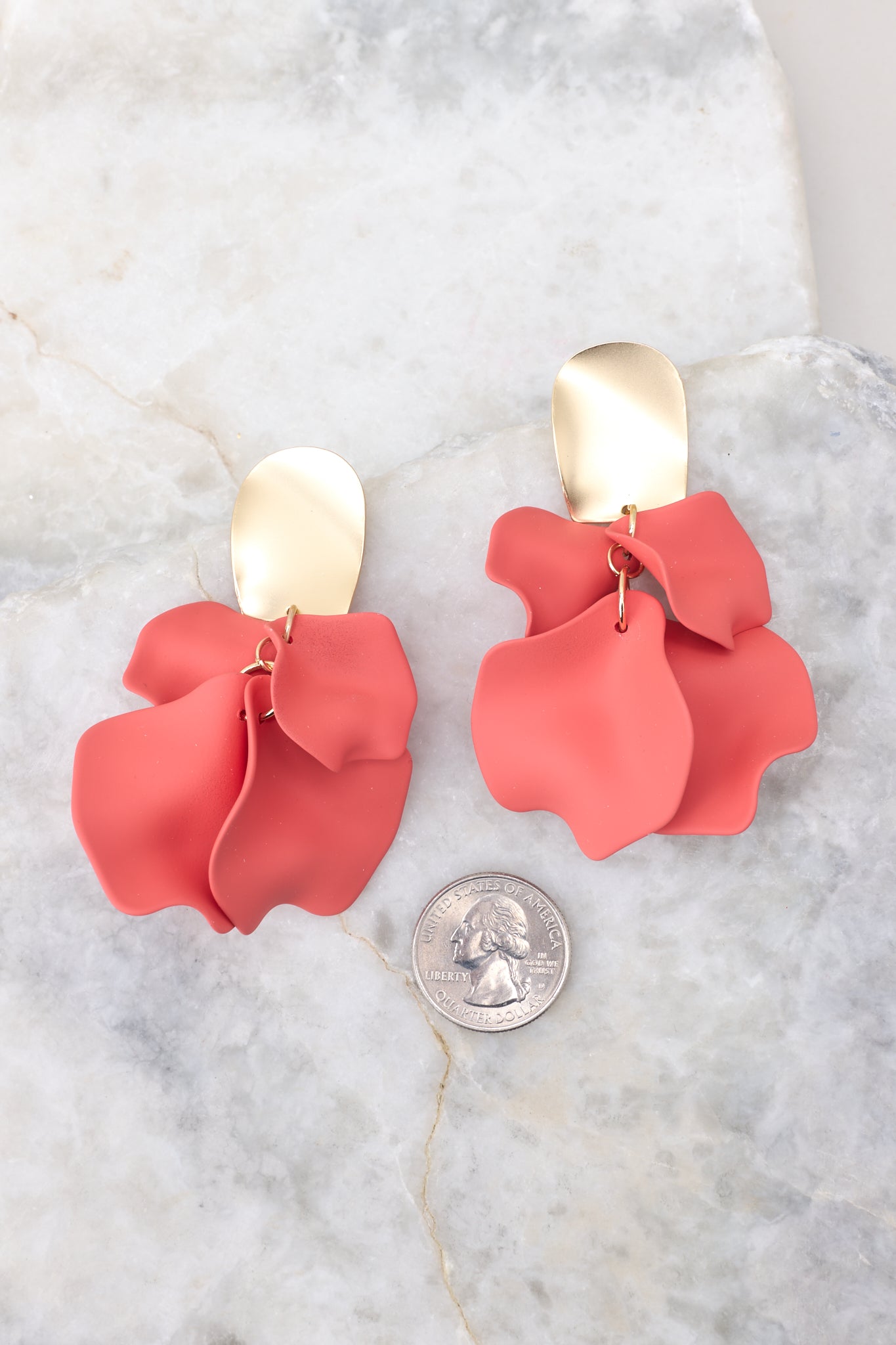 Size comparison shot of earrings featuring a hammered gold stud with coral petal shaped dangles, and a secure post backing.