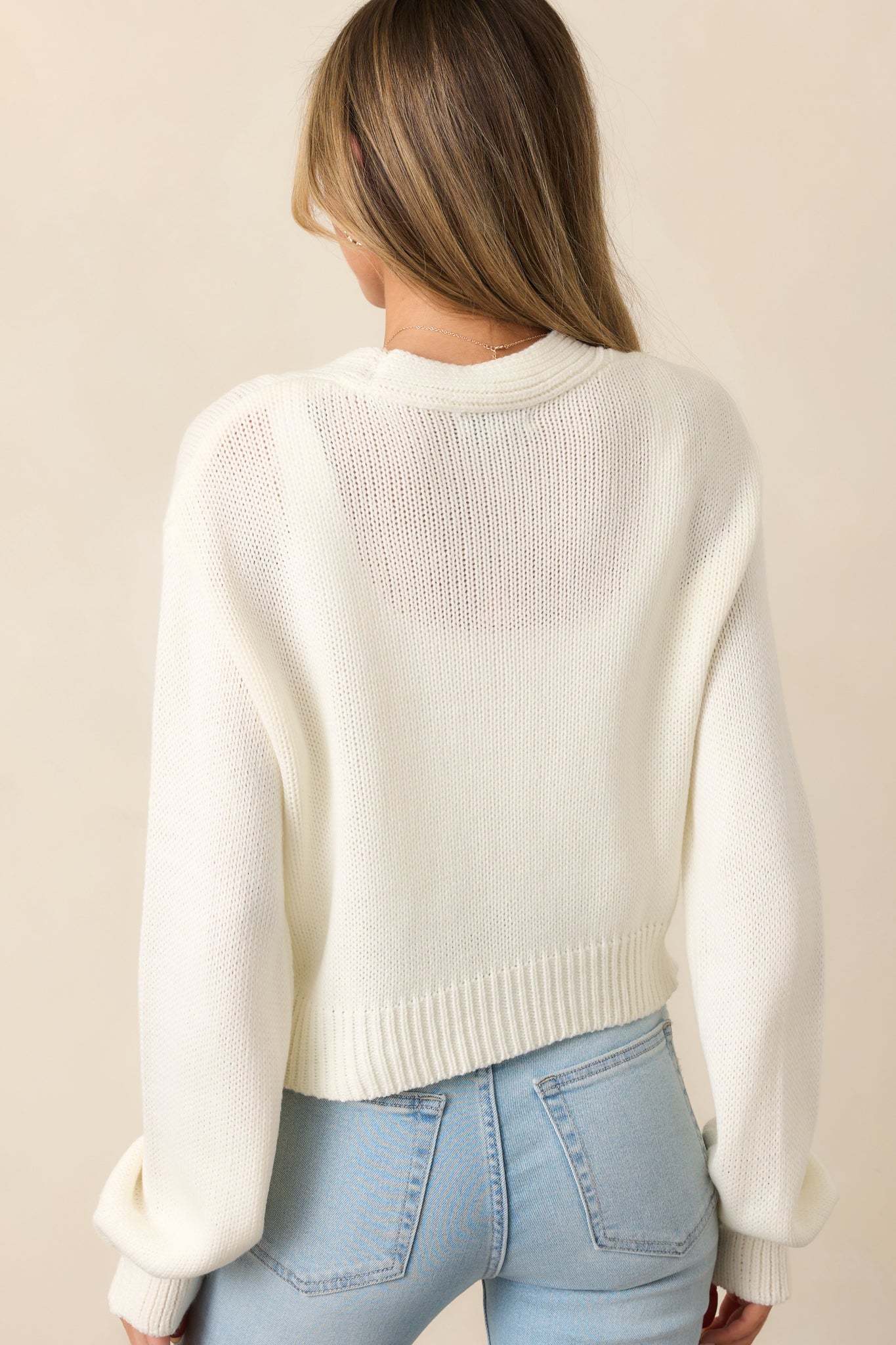 The back of this ivory cardigan keeps it simple and elegant with a clean knit finish and relaxed drape.