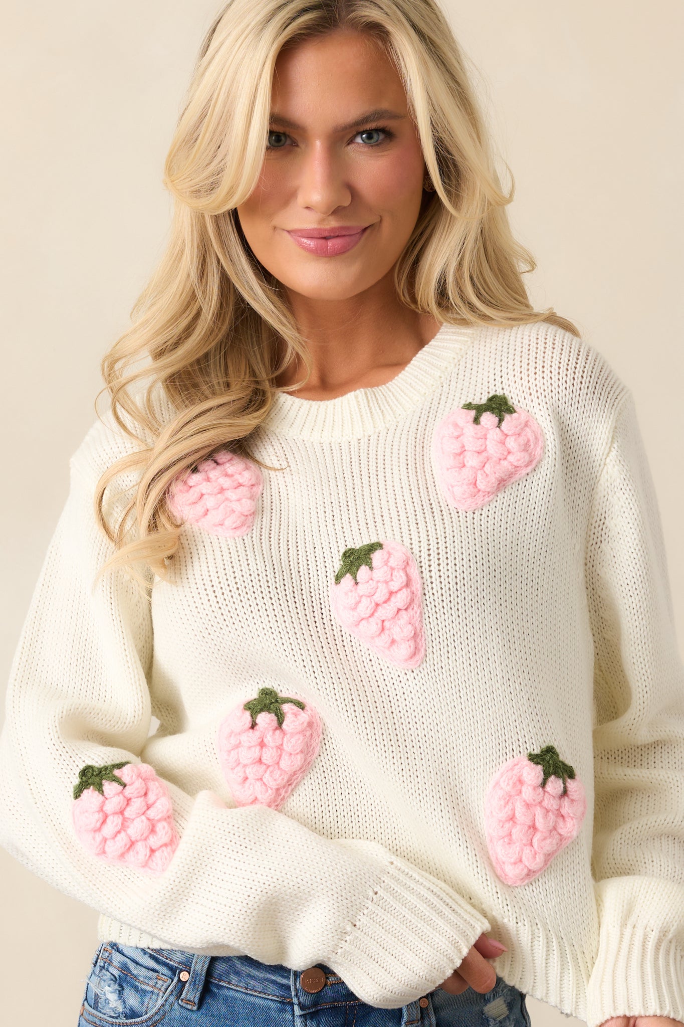 Long sleeves with ribbed cuffs complete the laid-back style of this ivory sweater, enhanced by the playful strawberry appliques.