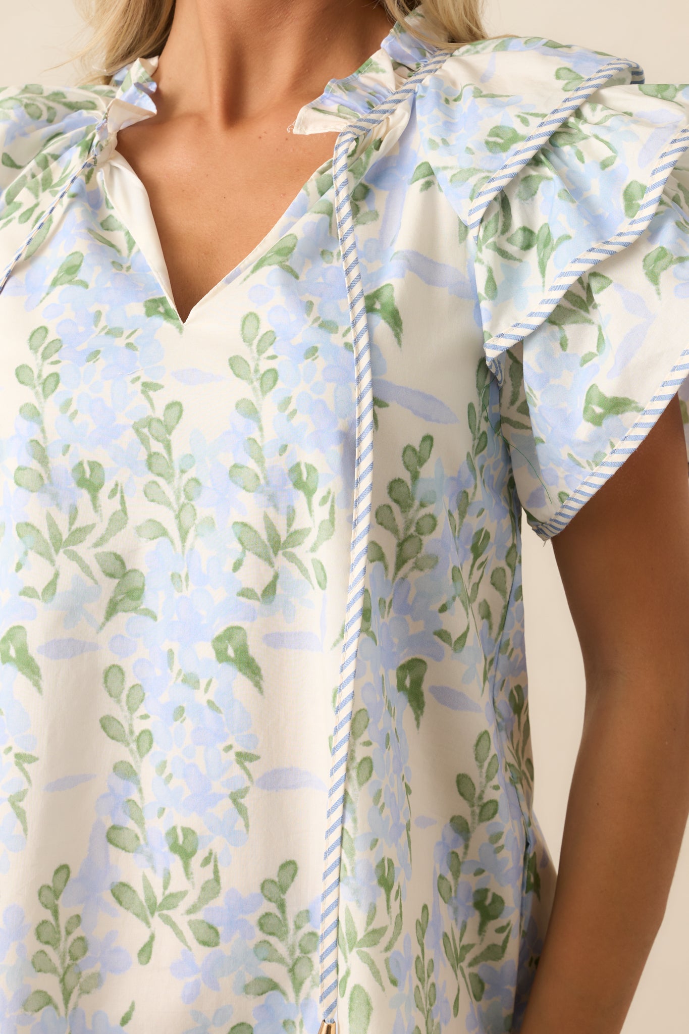 Close-up of the blue mini dress showcasing the self-tie neck detail and the texture of the ruffle neckline, highlighting the floral design.