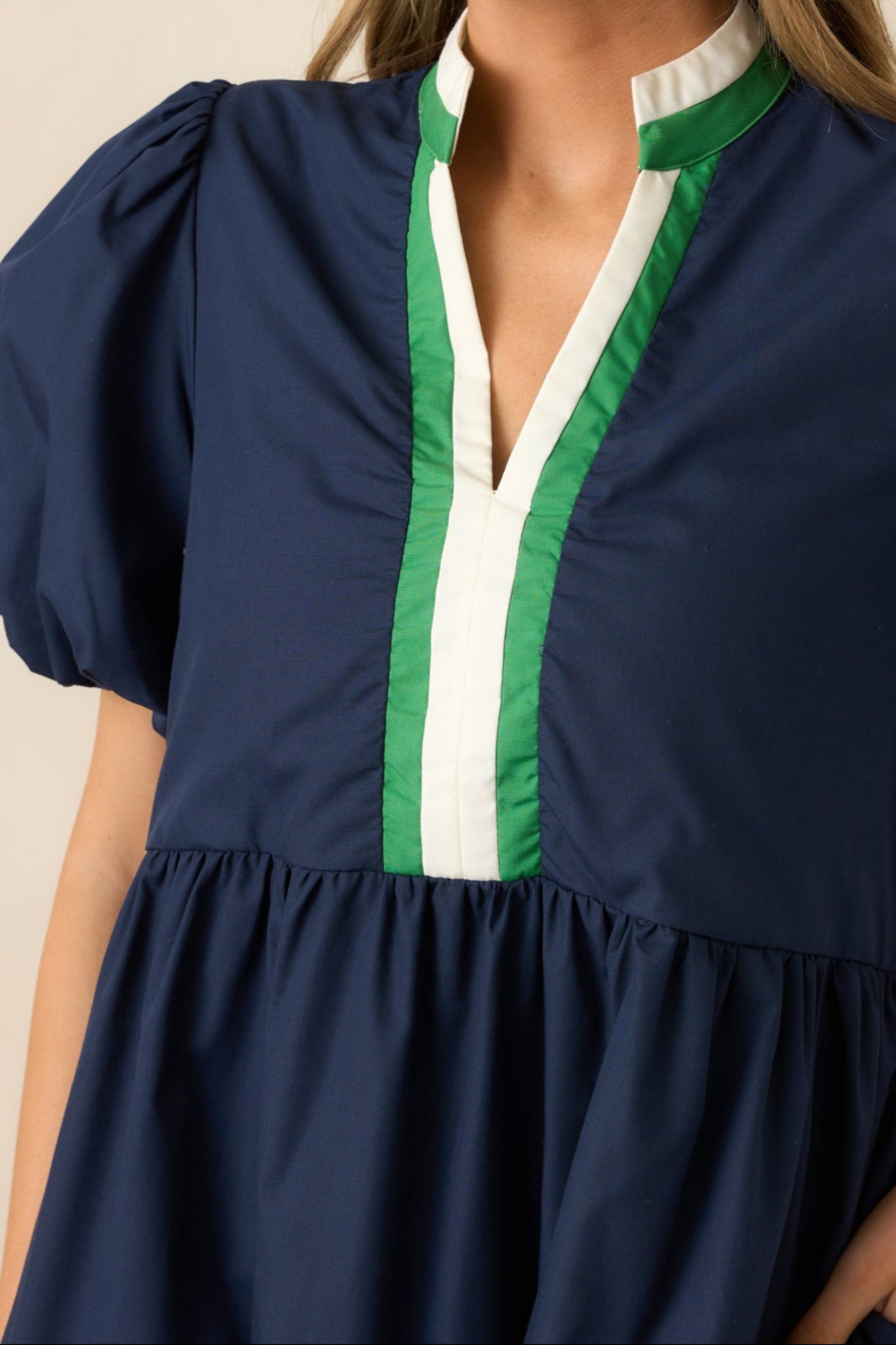 A close-up of the functional pockets and green and white stripe details on the skirt, adding both style and functionality to the navy mini dress.