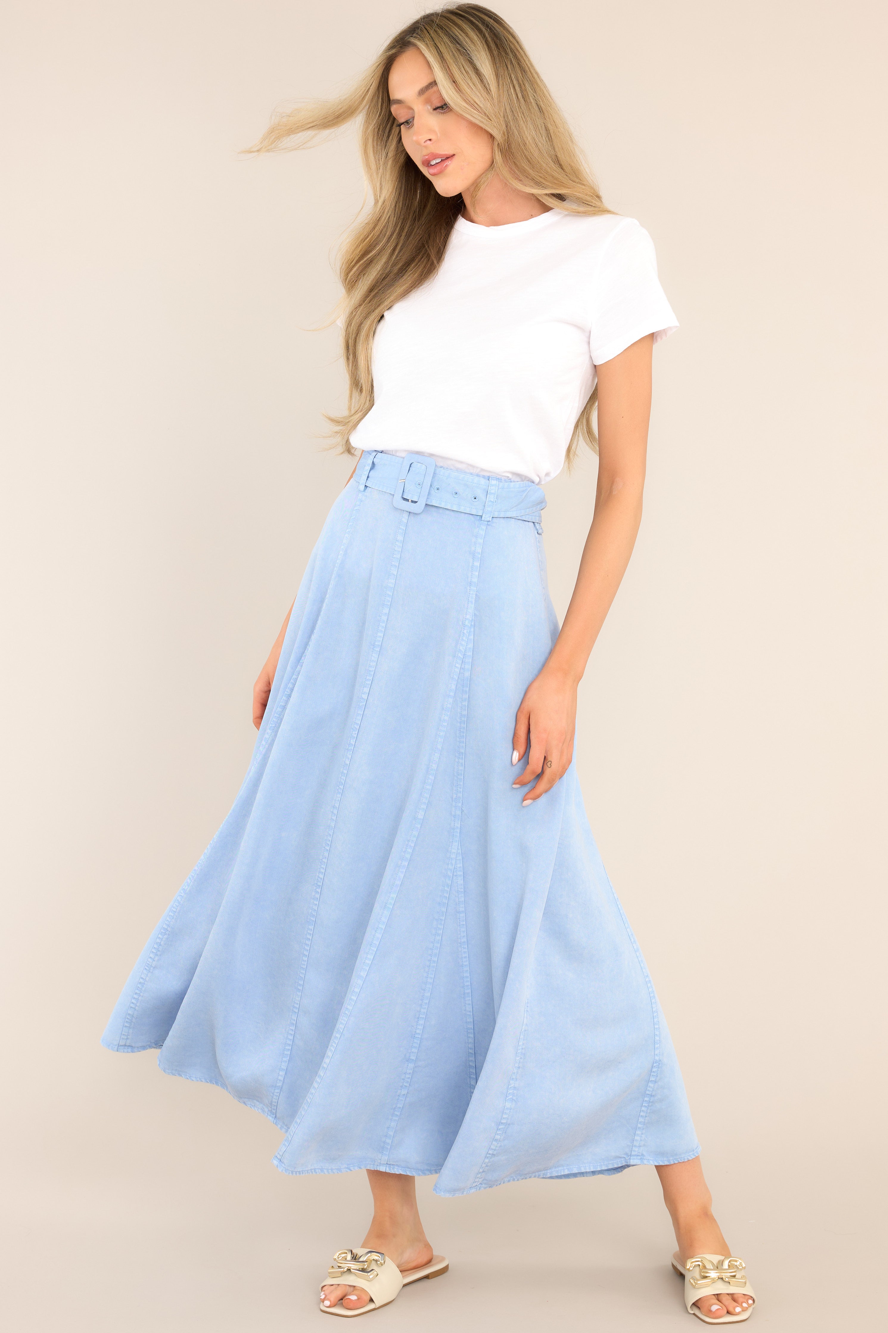 Full body view of this skirt that features a high waisted design, belt loops, a functional belt, a zipper with a hook closure in the back of the waist, and exposed seams.