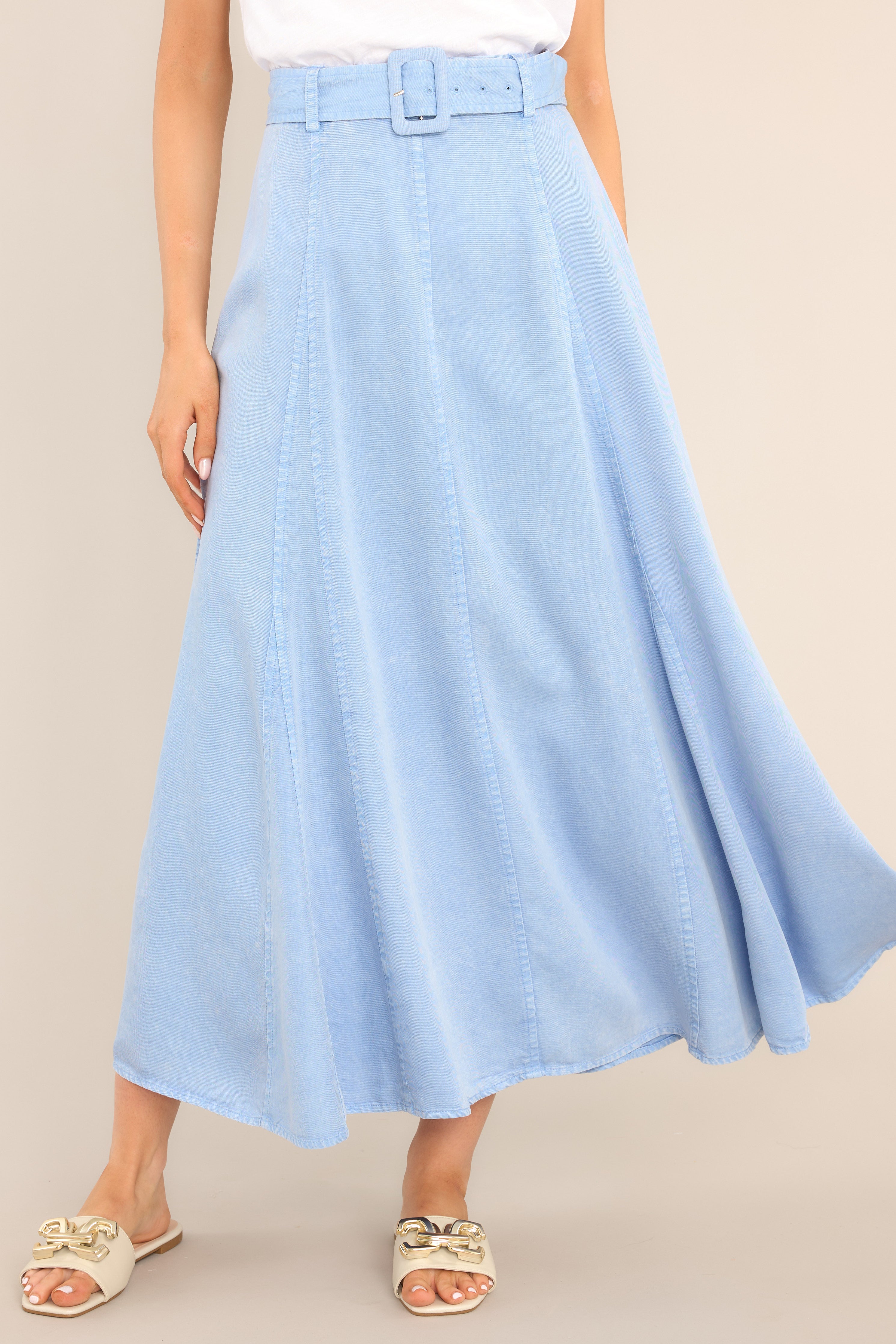 This blue skirt features a high waisted design, belt loops, a functional belt, a zipper with a hook closure in the back of the waist, and exposed seams.