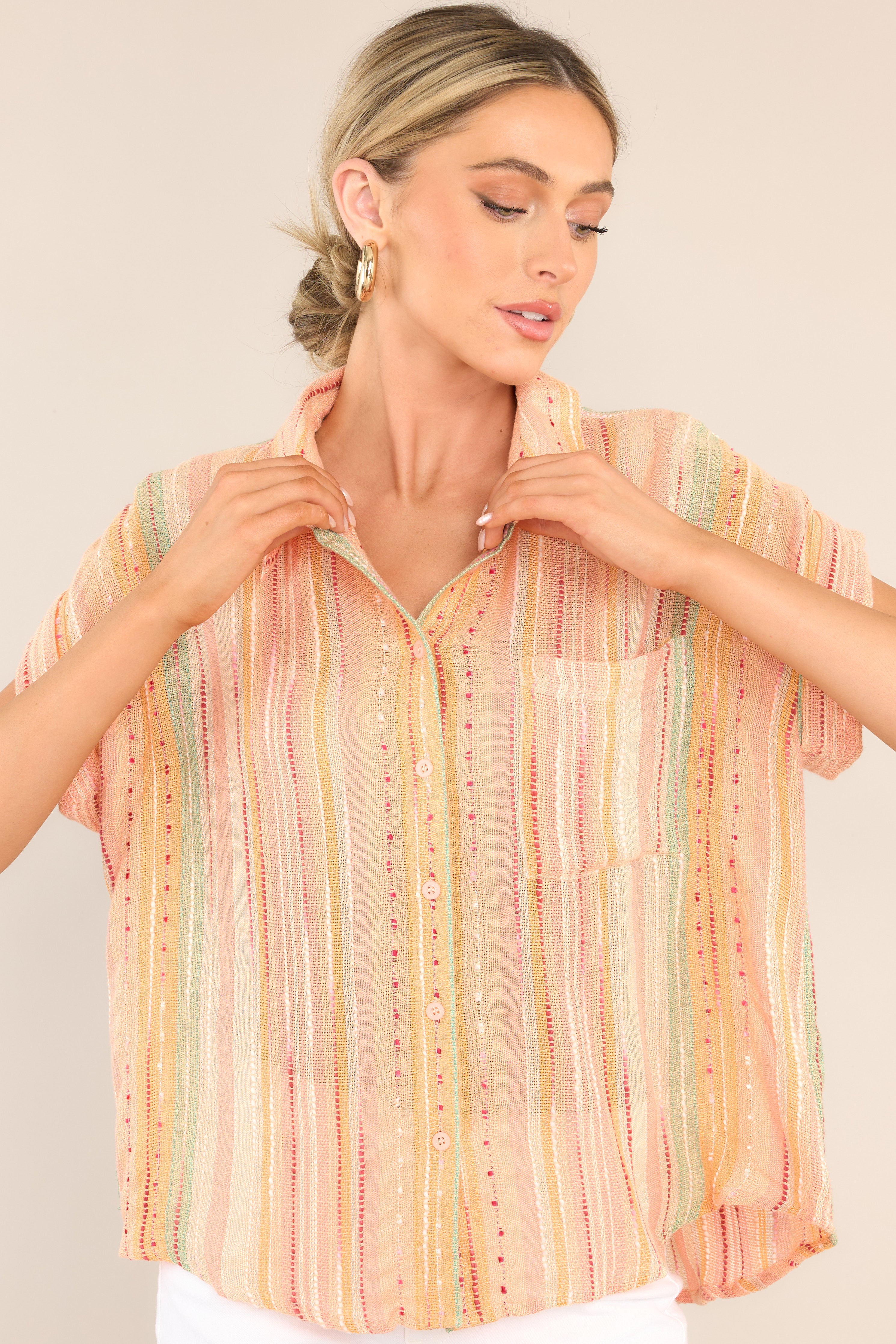 Front view of this top that features a collared neckline, functional buttons down the front, short sleeves with folded cuffs, a functional front pocket, and a round hemline.