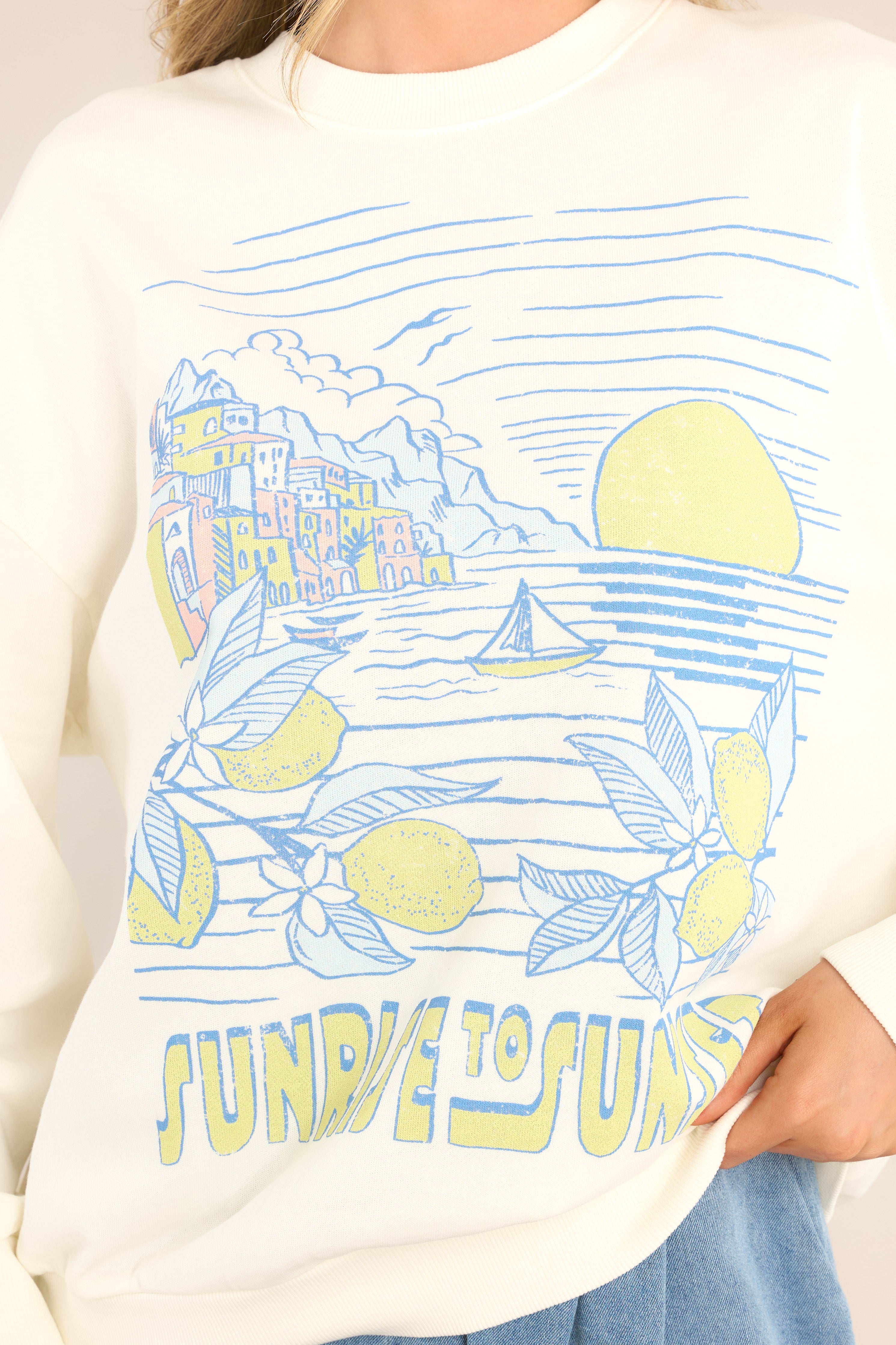 Close up view of this sweatshirt that features a crew neckline, dropped shoulders, a summery graphic that says "SUNRISE TO SUNSET", ribbed cuffed sleeves, and a ribbed hemline.