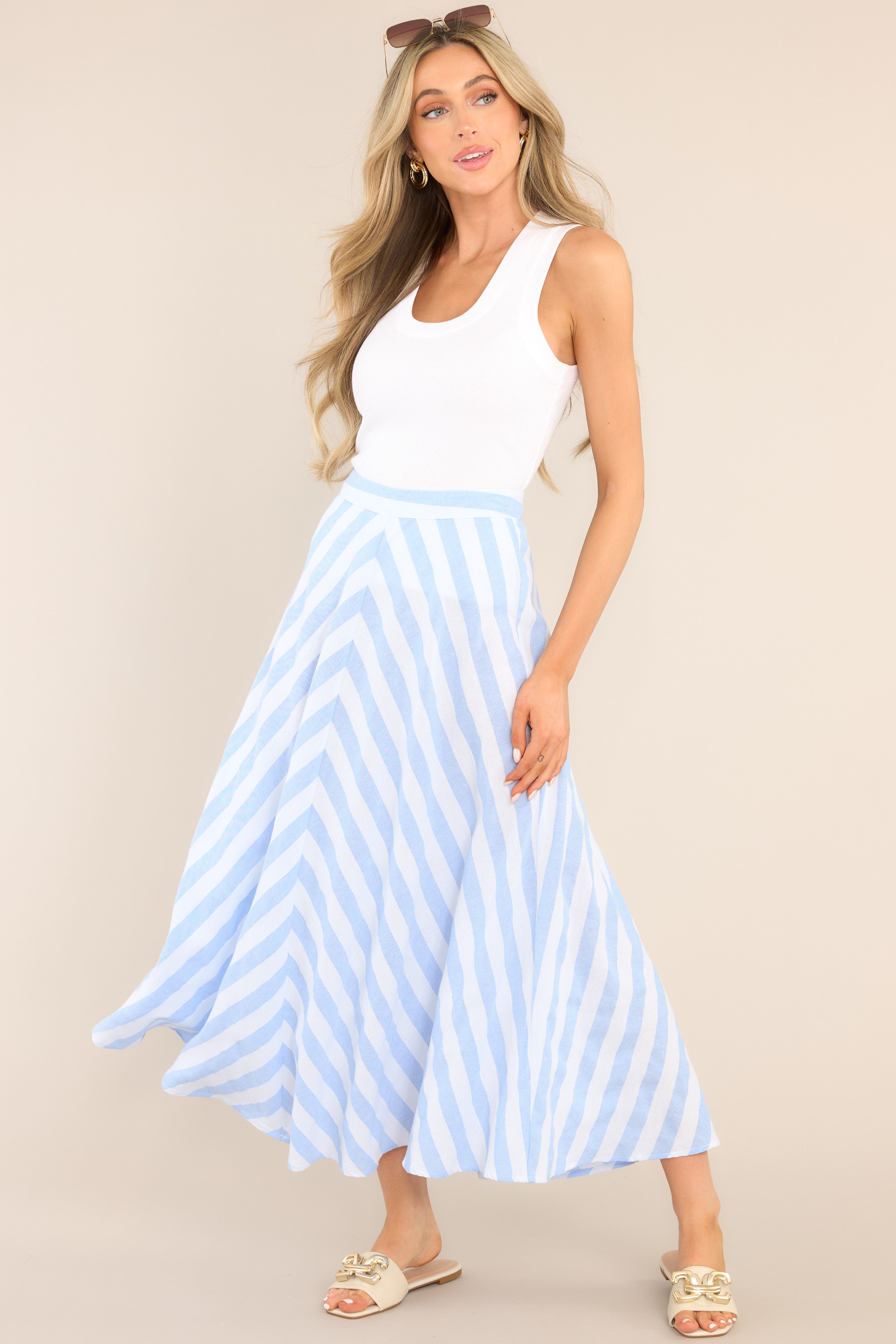 This blue and white skirt features a high waisted design, a functional zipper and hook closure in the back, a diagonal striped pattern, and a flowy fabric.