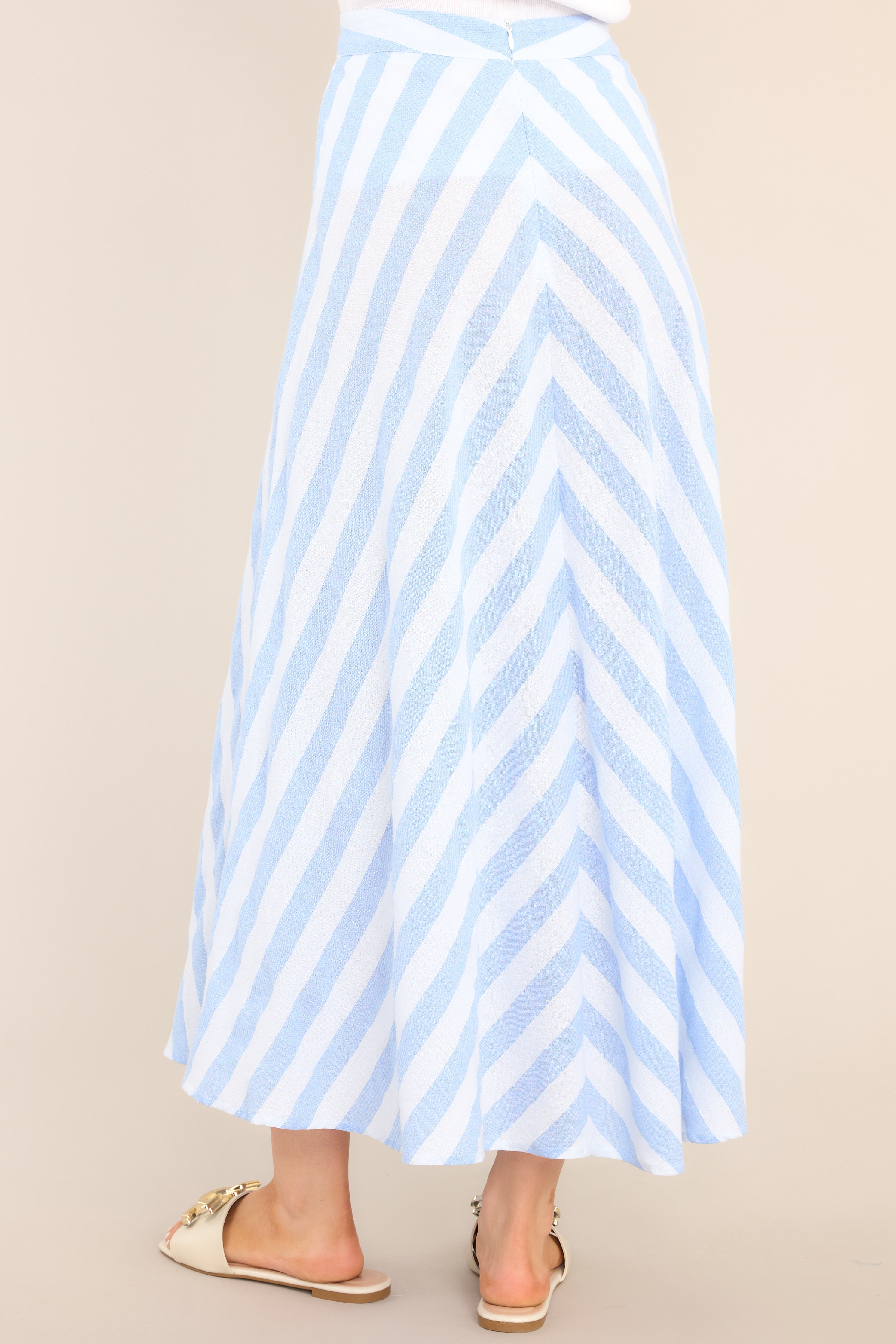 Back view of  this skirt that features a high waisted design, a functional zipper and hook closure in the back, a diagonal striped pattern, and a flowy fabric.