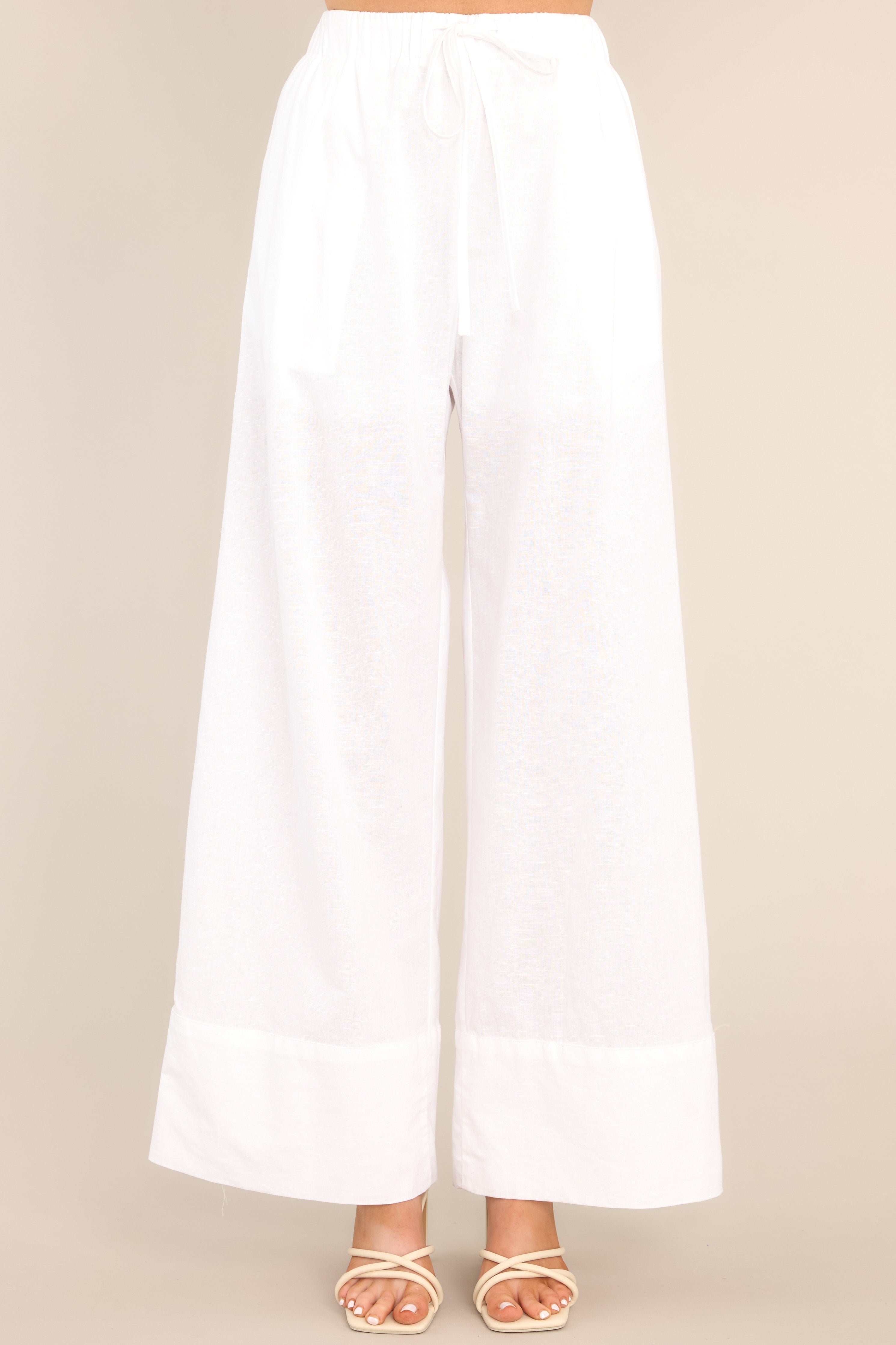 Front view of these pants that feature a high waisted design, an elastic waistband with a self-tie feature, functional pockets, and a thick ankle cuff. 