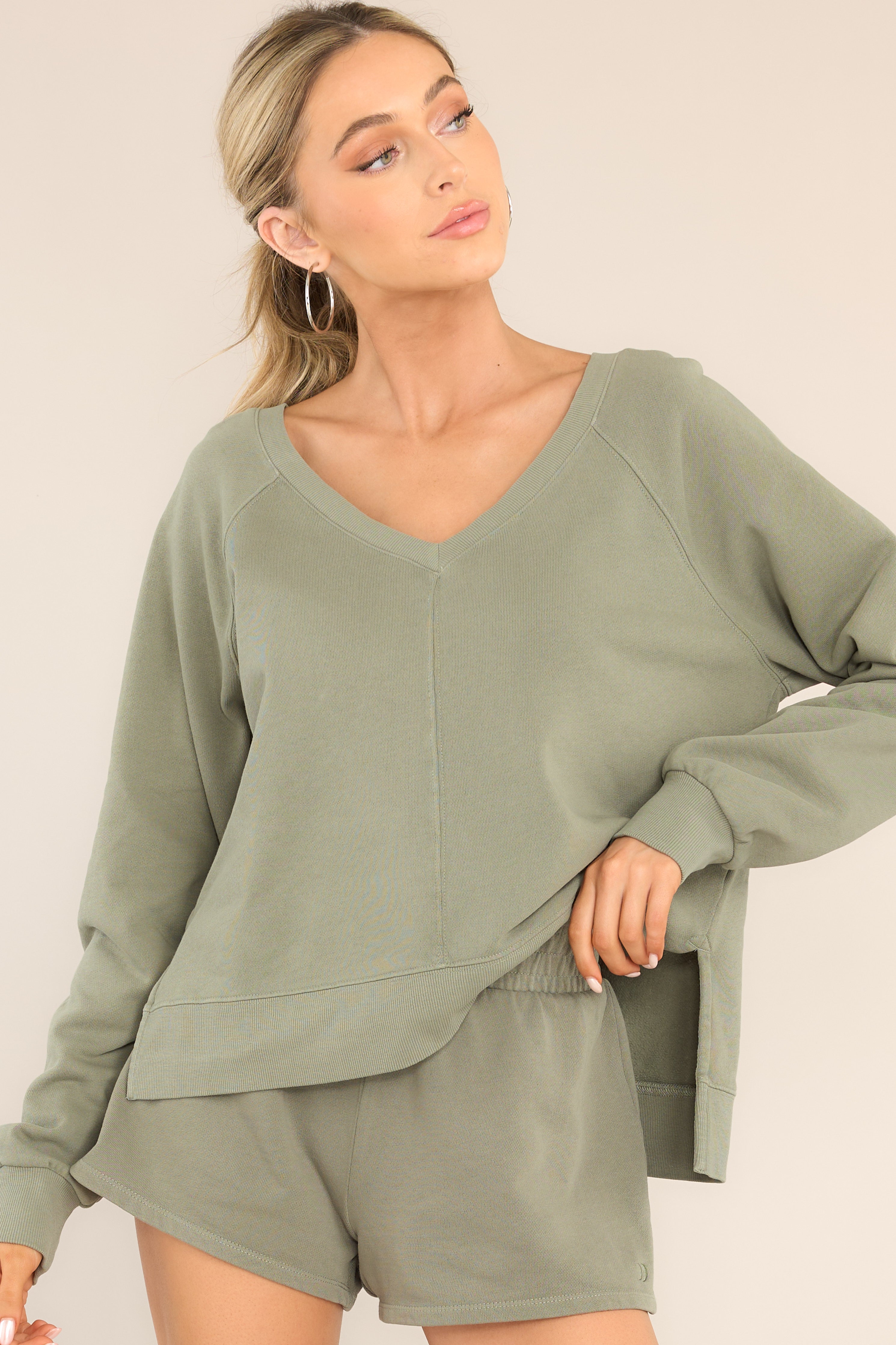 Front view of this sweatshirt that features a ribbed wide v-neckline, an intentional front-seam detail, fitted ribbed sleeve cuffs, a small split hem on the sides, and an open v-shaped back detail.