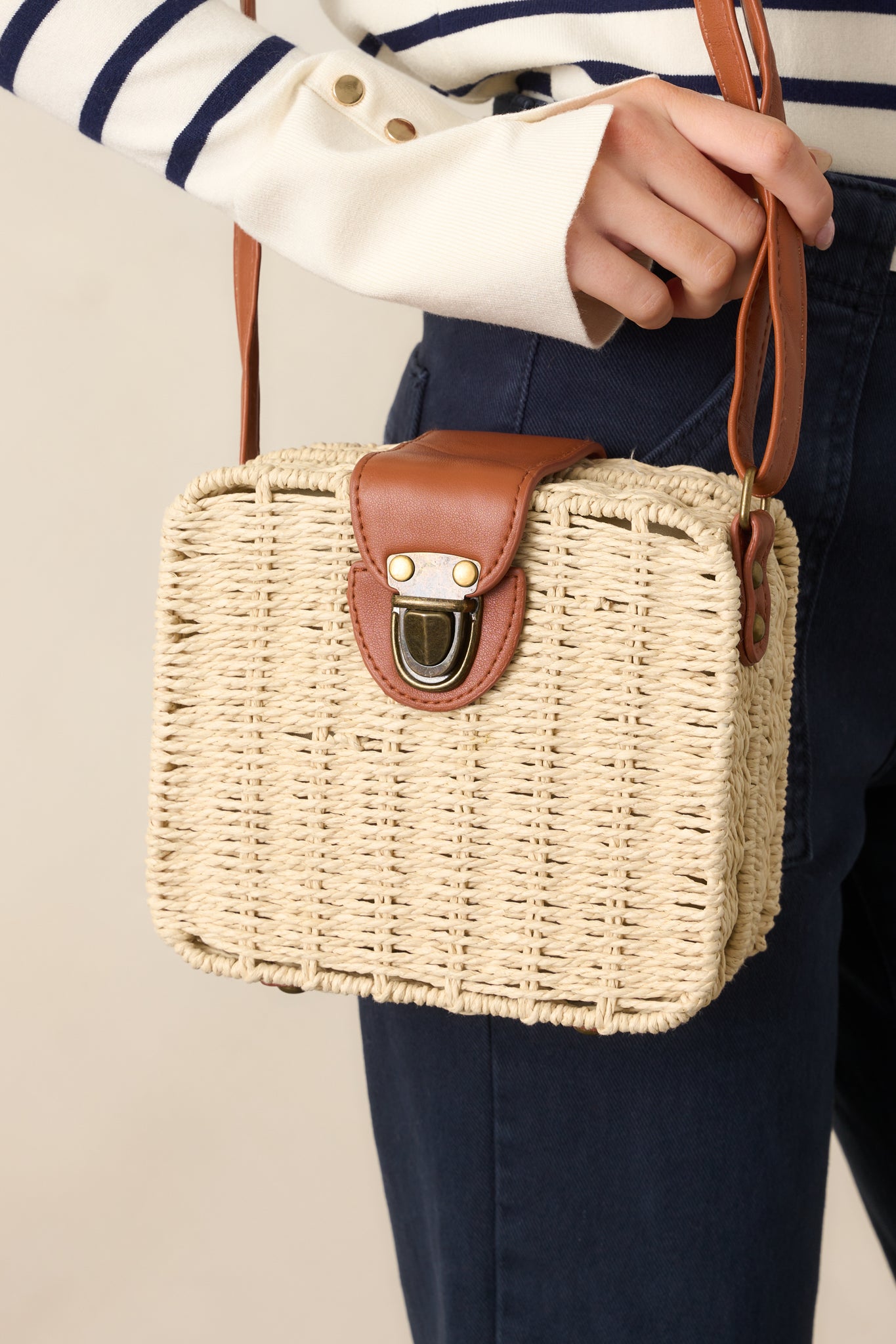 A detailed shot of the handbag’s tuck lock closure and the texture of the white wicker material.