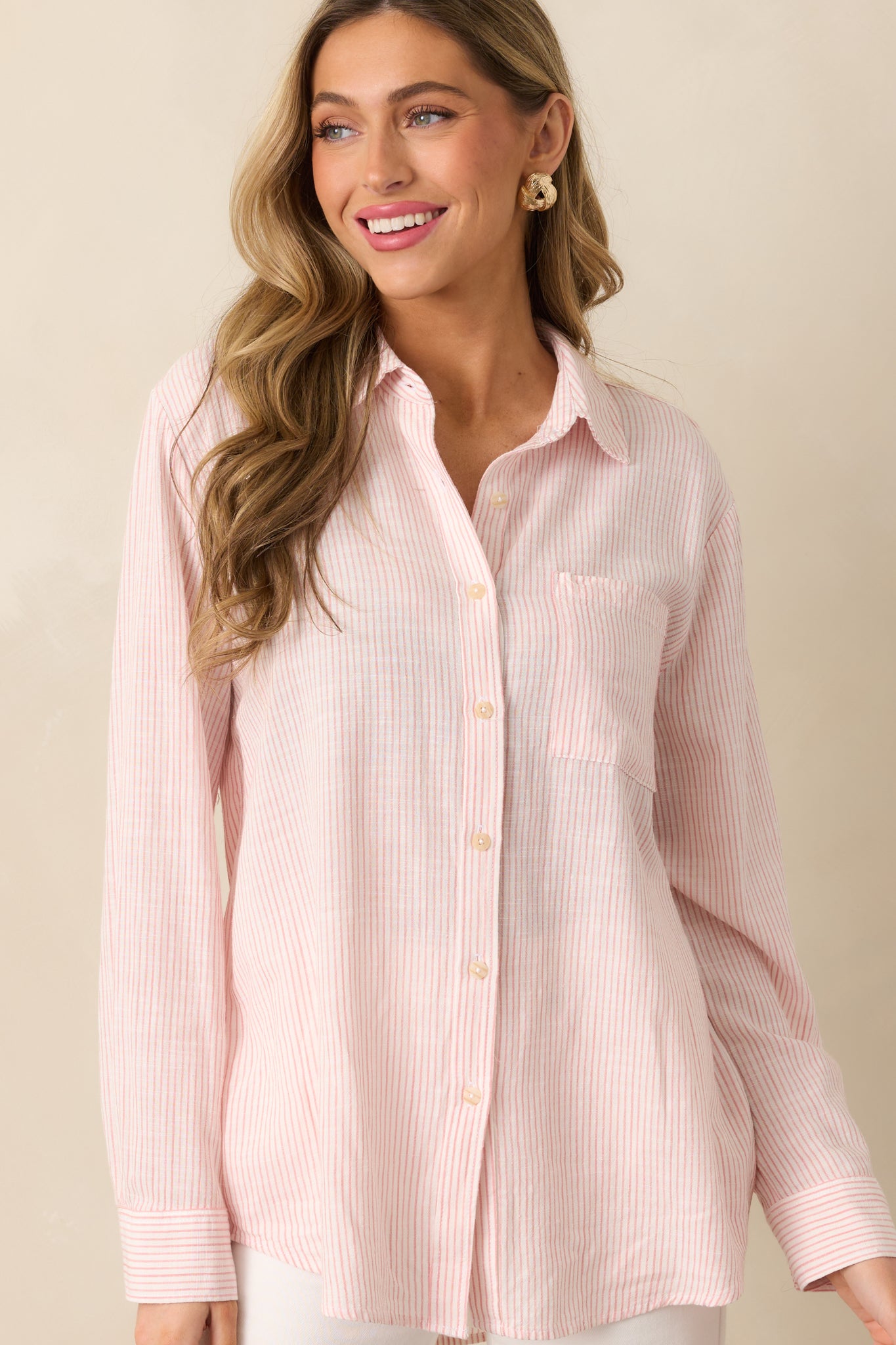 A front shot of the pink top highlighting the long sleeves with button cuffs and the light linen blend fabric.