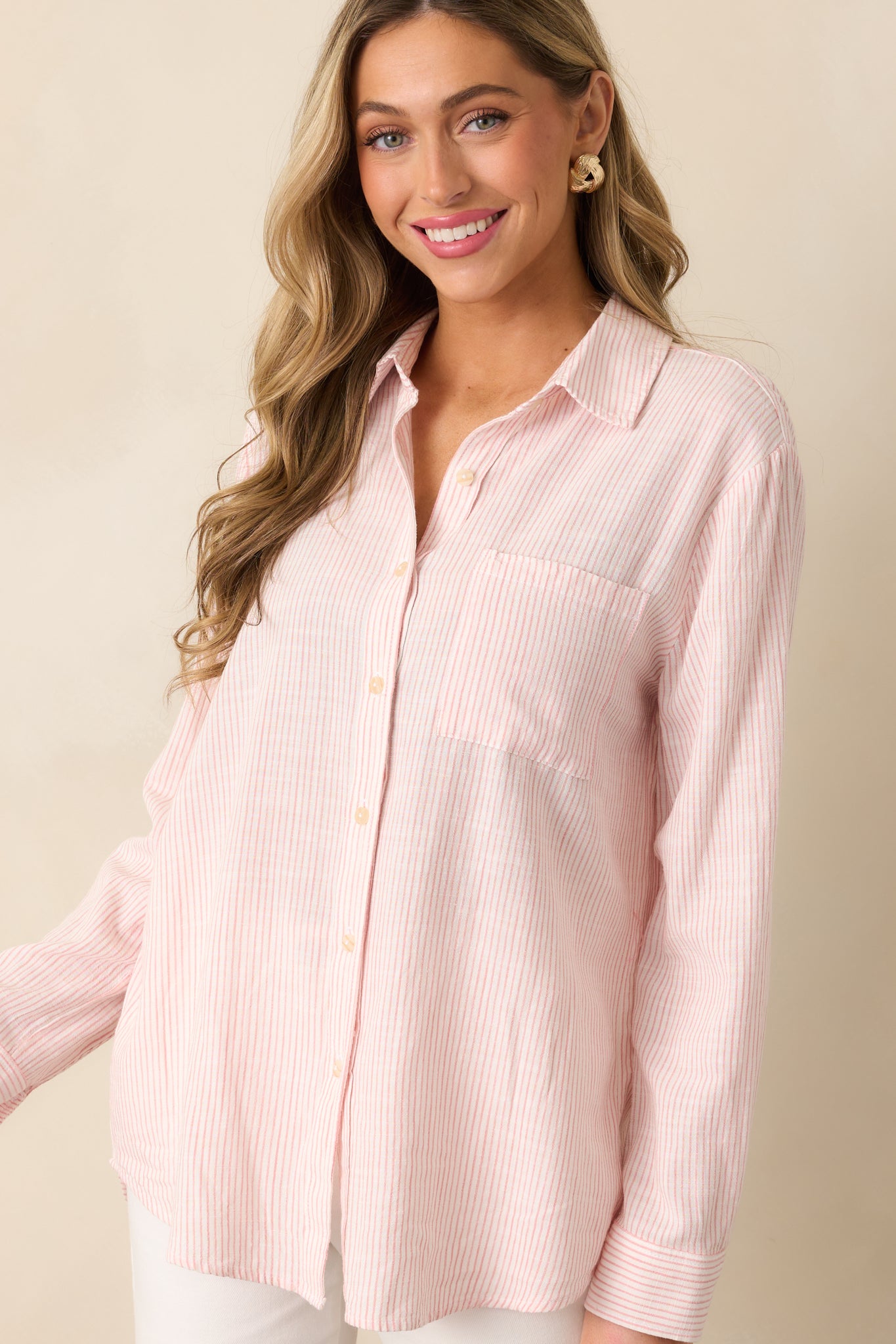 A front view of the pink top showcasing its collared neckline, button-front design, and striped print.