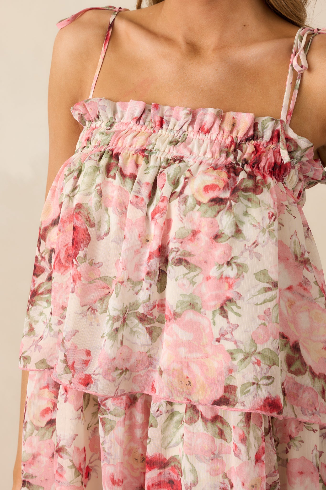 A close-up of the dress’s smocked neckline and self-tie shoulder straps, showcasing the fine details of the floral print and fabric texture.