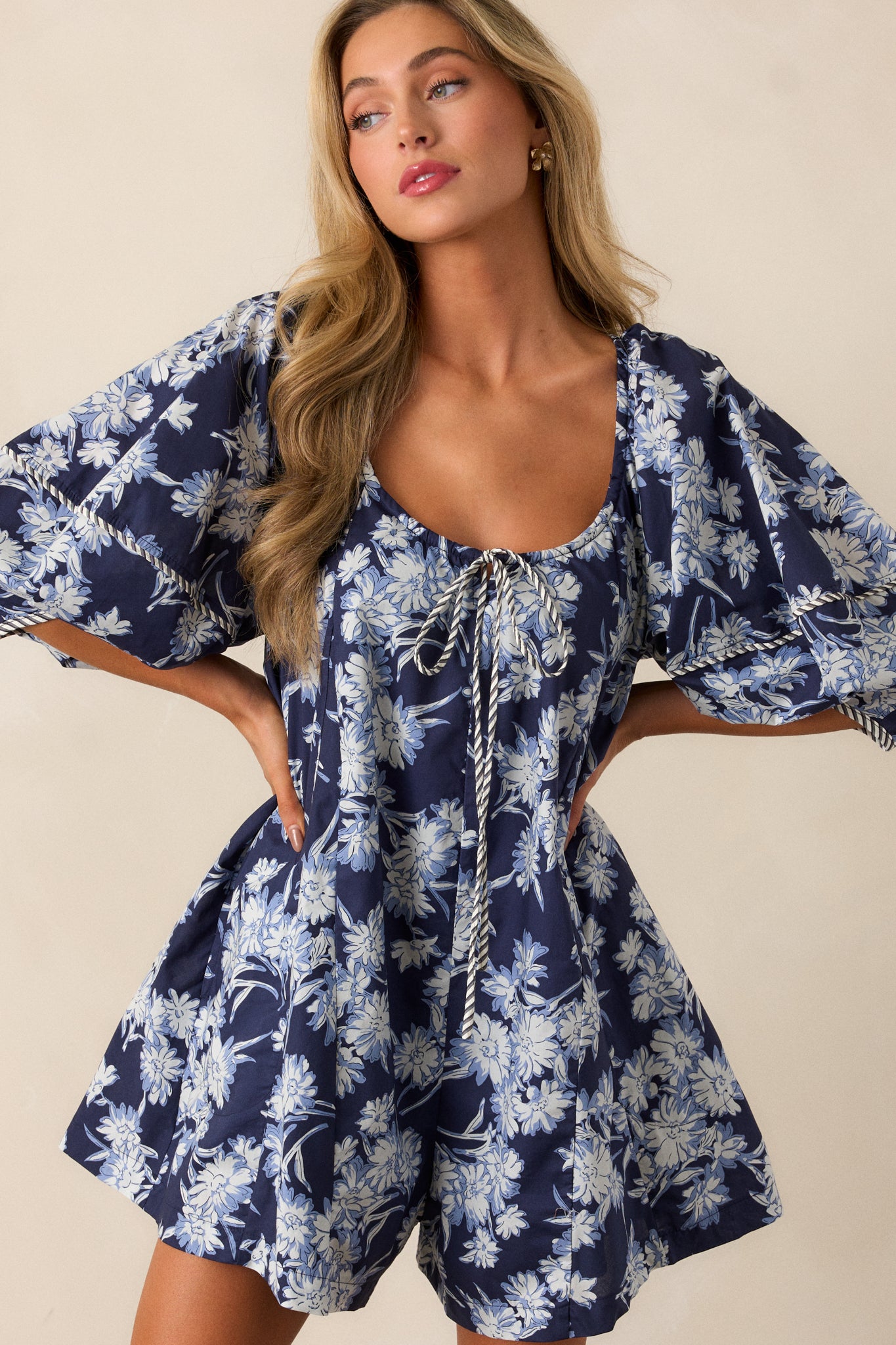 Close-up of the self-tie keyhole scoop neckline on the romper, showing the intricate floral pattern around the neckline and the delicate bow detail.