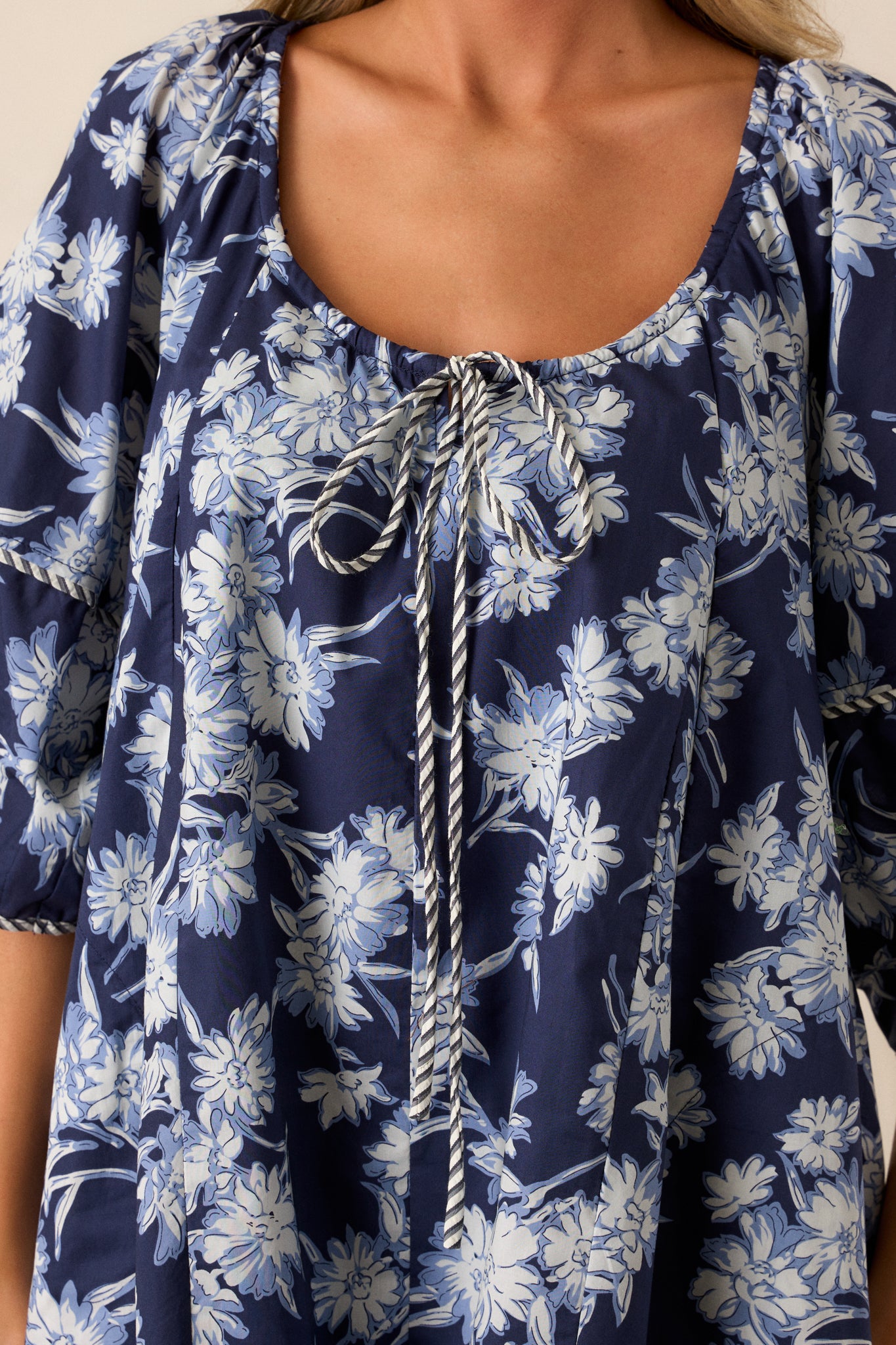 Extreme close-up of the blue and white floral pattern on the romper, showcasing the vivid print and smooth texture of the fabric.