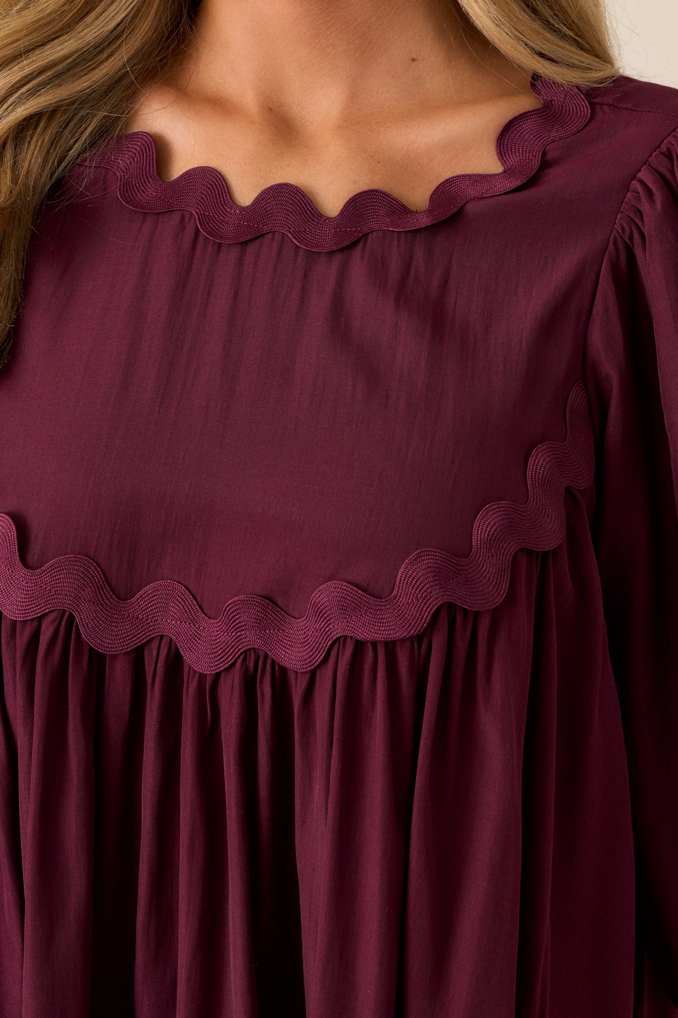 Close-up of the scalloped neckline and yoke detailing on the dark sangria top, capturing the texture and design elements.