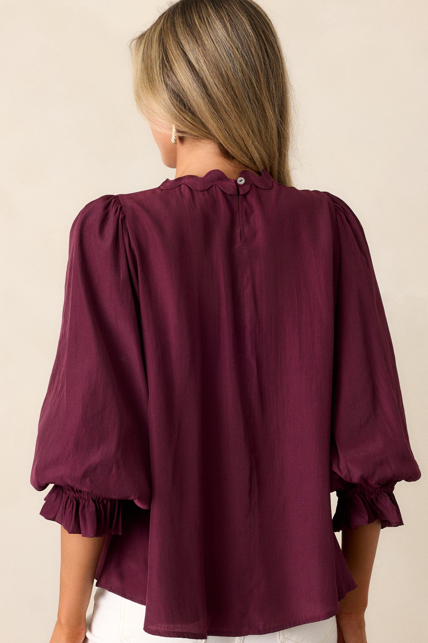 Back view of the dark sangria top, highlighting the single back button and flowy design with scalloped neckline.