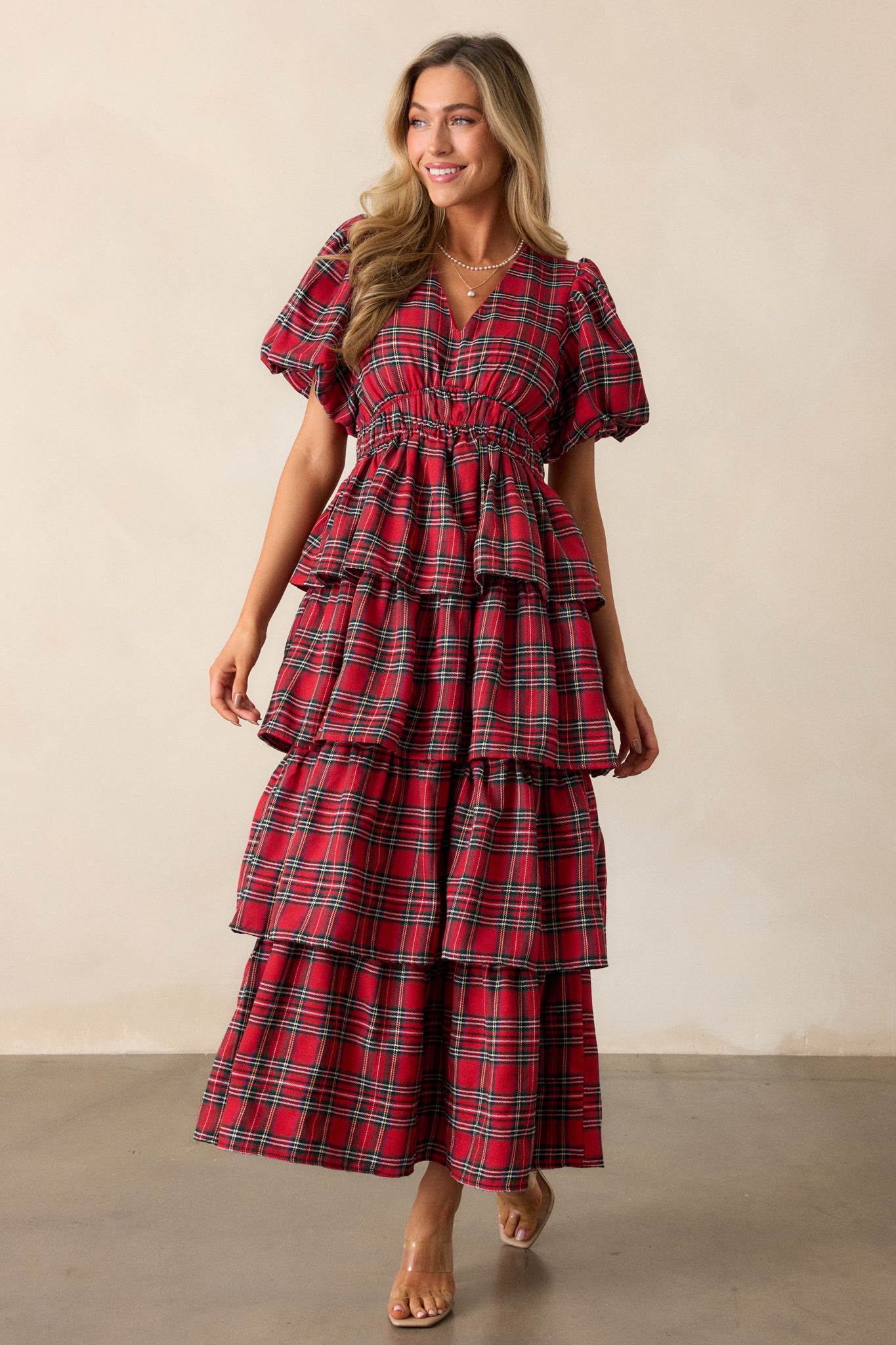 Full body image capturing the puff sleeves, emphasizing the dress's elegant silhouette and the contrast between the red fabric and plaid design.
