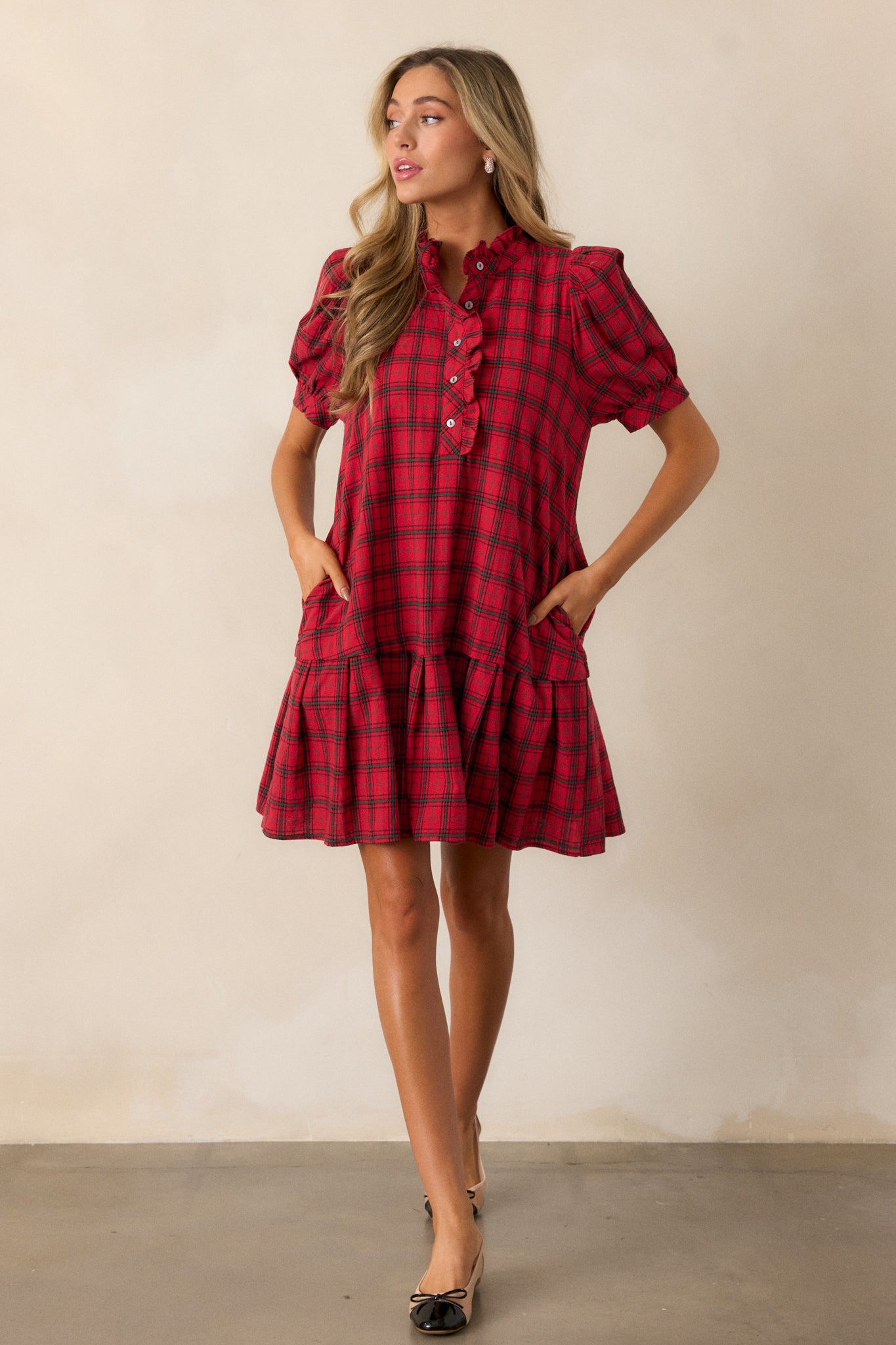 Full view of a red mini dress featuring a ruffle collar with a v-neckline, functional buttons, a plaid design, and a flared cut with a drop waist hem.