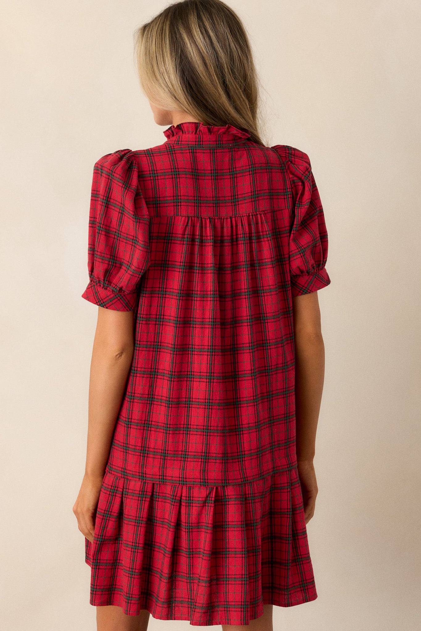 Back view of the red dress, displaying the plaid design, drop waist hem, and flared silhouette from behind.