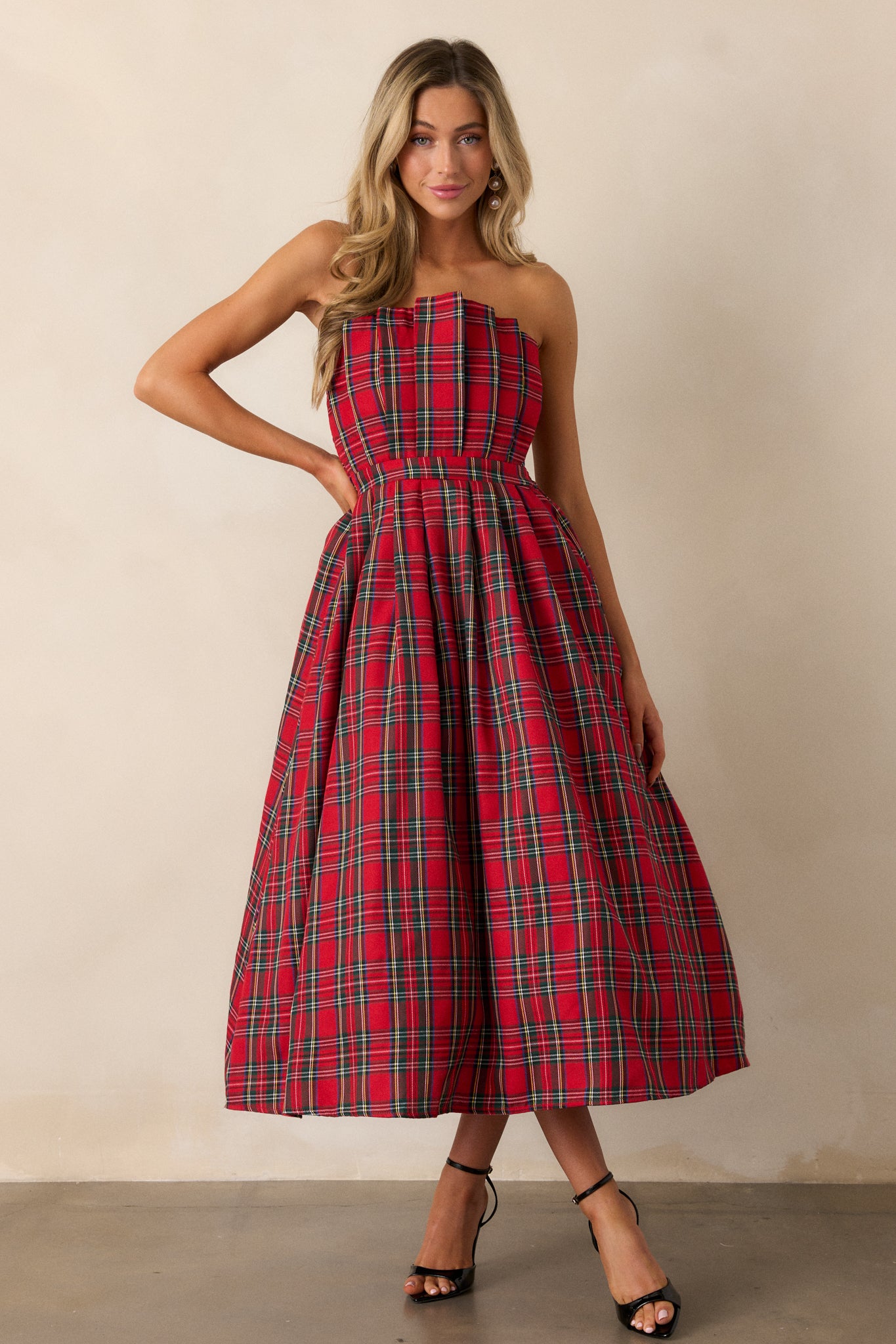 A full-length view of the red plaid dress, showcasing the strapless design and pleated bodice that creates an elegant silhouette.