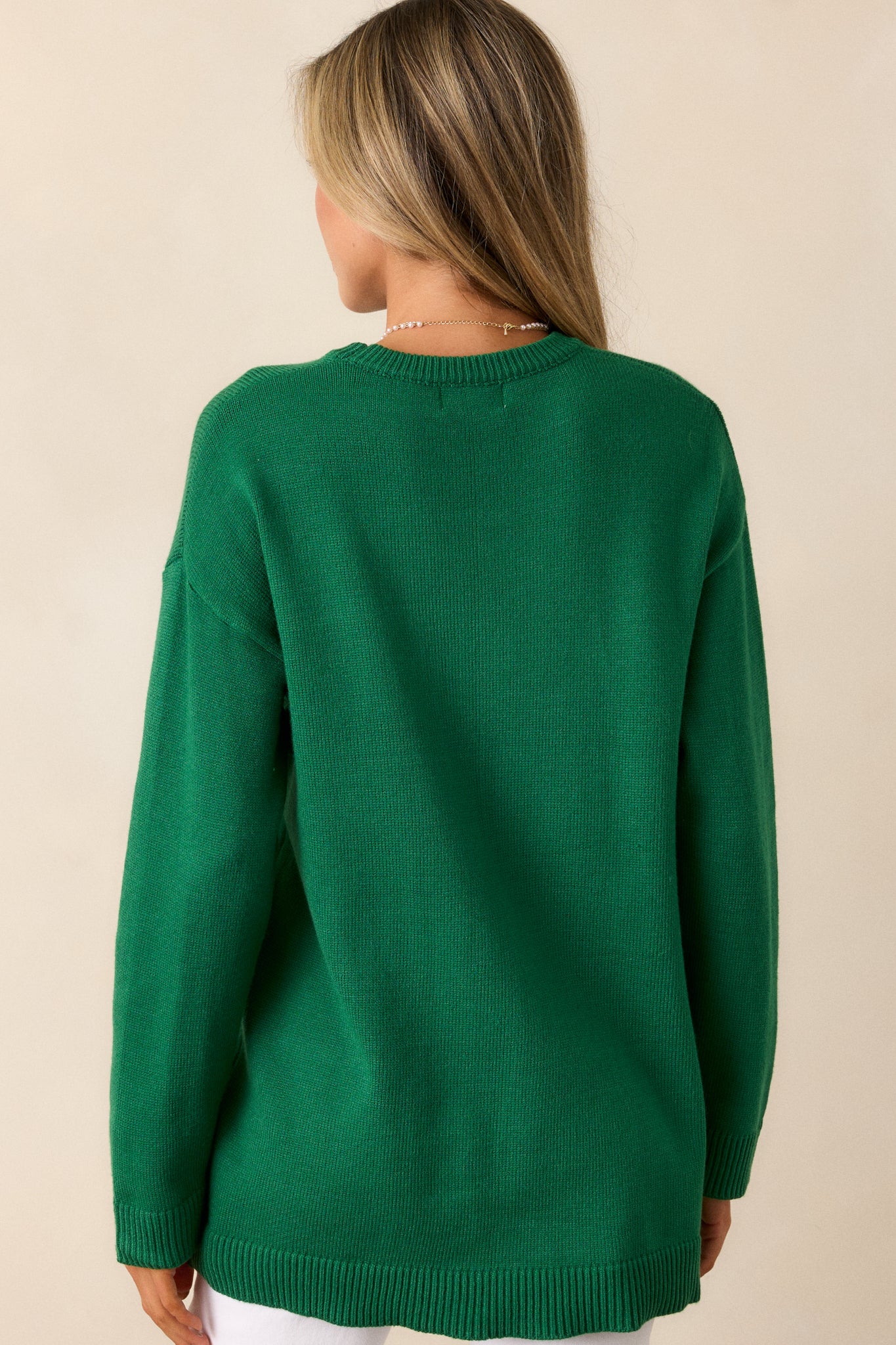 Back view of the sweater, showing the relaxed fit and simplicity of the design with ribbed detailing around the neck and cuffs.