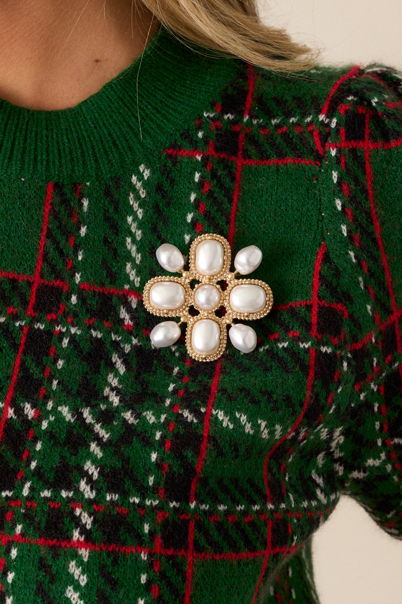 This gold brooch features textured gold hardware, a medium sized round faux pearl middle, four large square sections with faux pearl decorations, four little arms with one faux pearl attached to each arm and a hinge and catch closure.